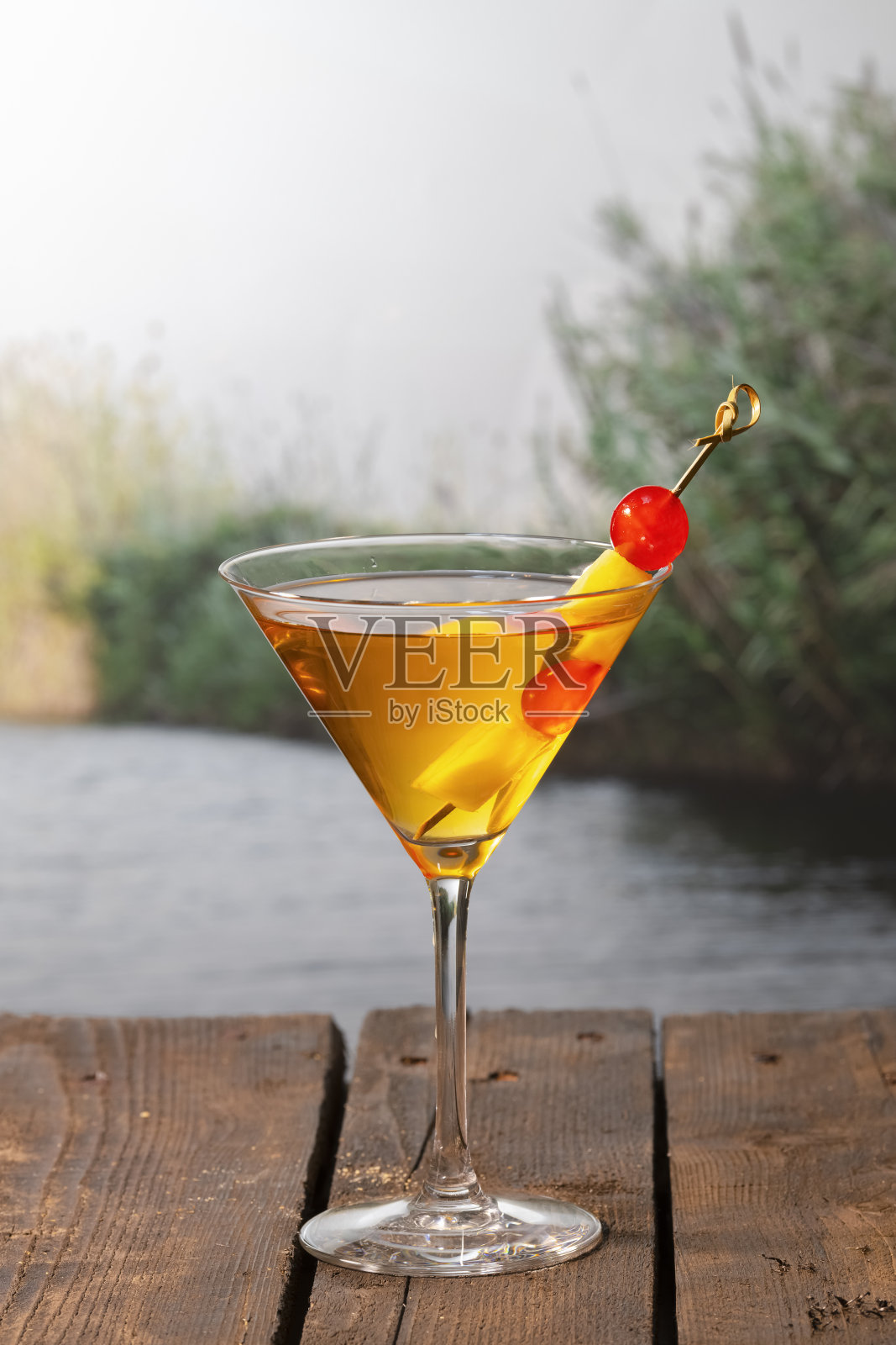 一种看起来很美味的鸡尾酒，用樱桃和菠萝串在木桌上照片摄影图片