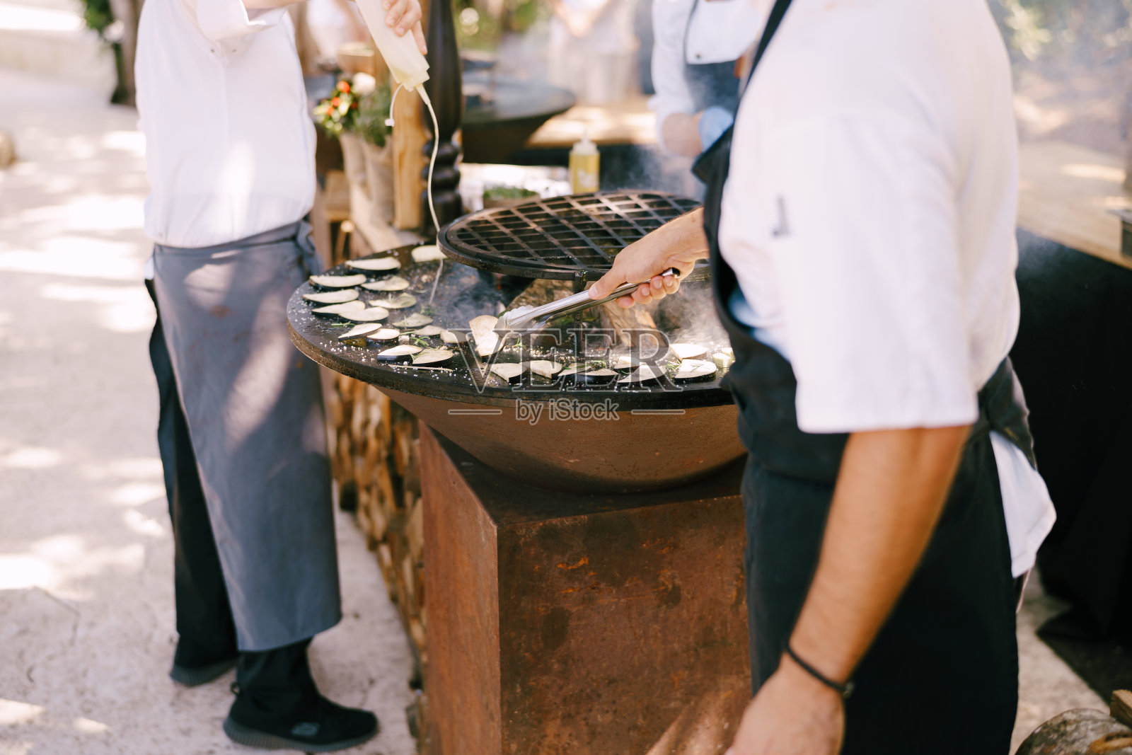 厨师烤西葫芦。烤蔬菜。碗状的圆形烤架，里面有火。照片摄影图片