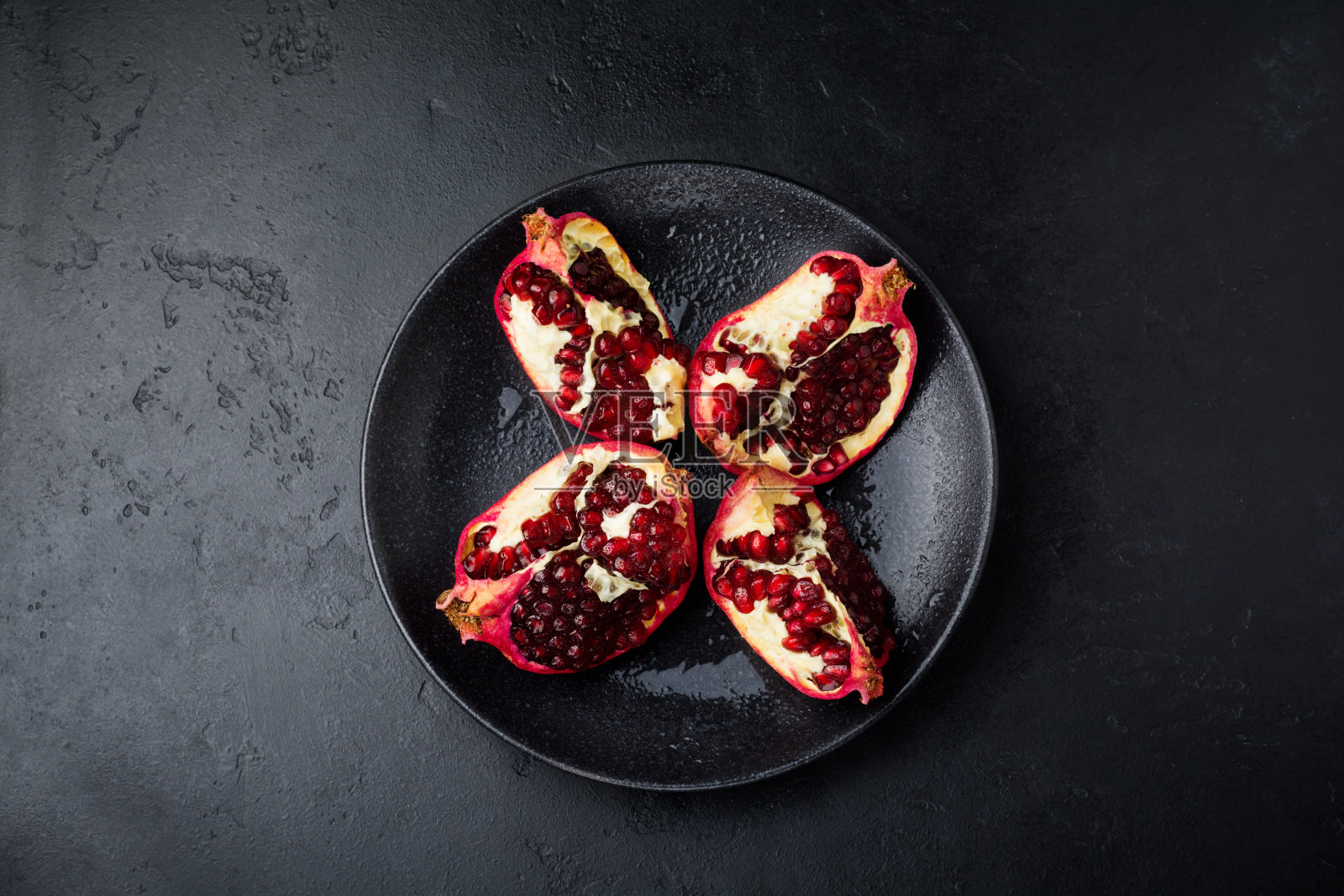 新鲜成熟的石榴，在黑色混凝土或石头上切成块。有选择性的重点。文本。前视图。照片摄影图片