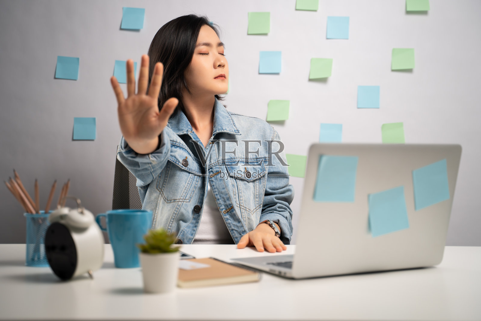 亚洲妇女在笔记本电脑上工作，显示手在家里办公室停止标志。亲密。居家办公COVID-19概念。照片摄影图片