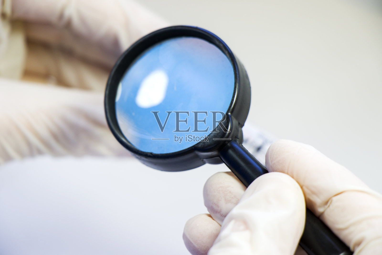 用放大镜和戴着手套的人手，观察和研究某样东西。实验室的情况。照片摄影图片