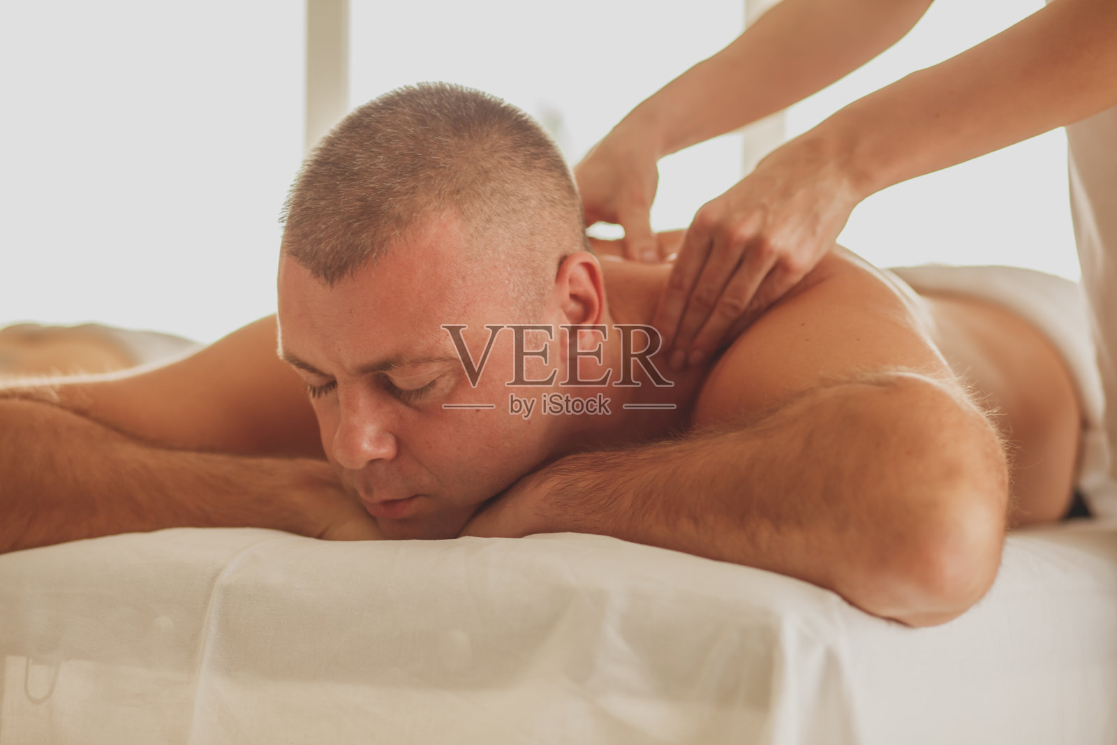 男人在温泉享受轻松的背部按摩照片摄影图片