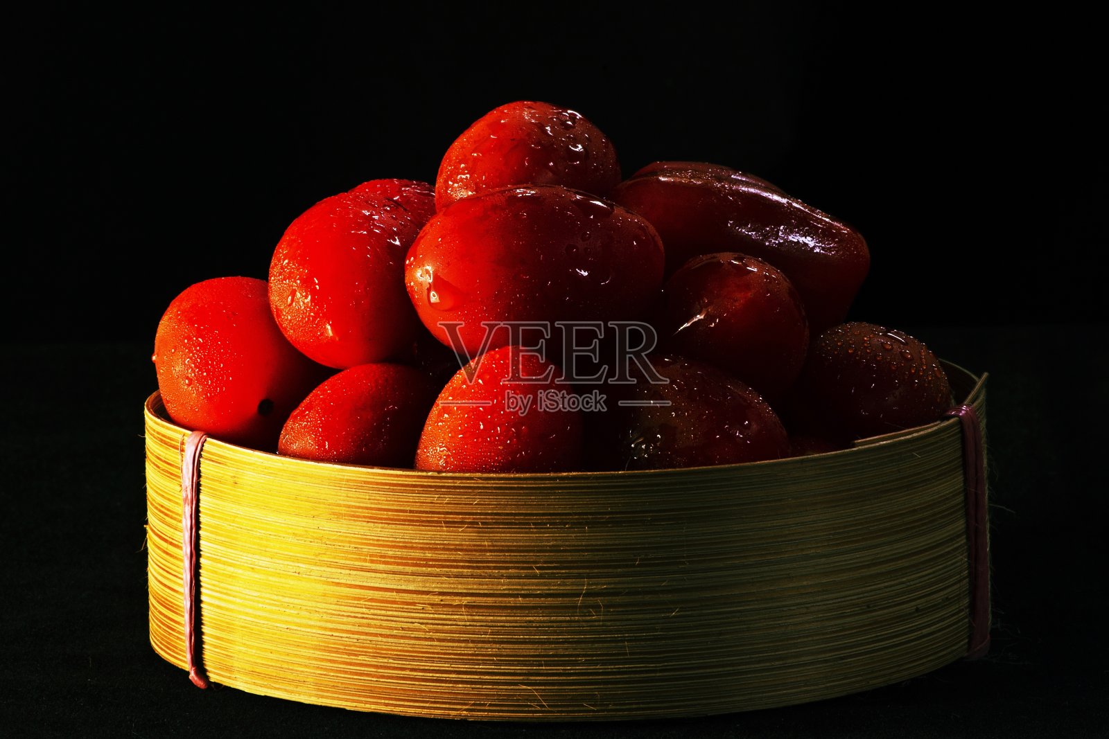 番茄在篮子黑色的背景。照片摄影图片