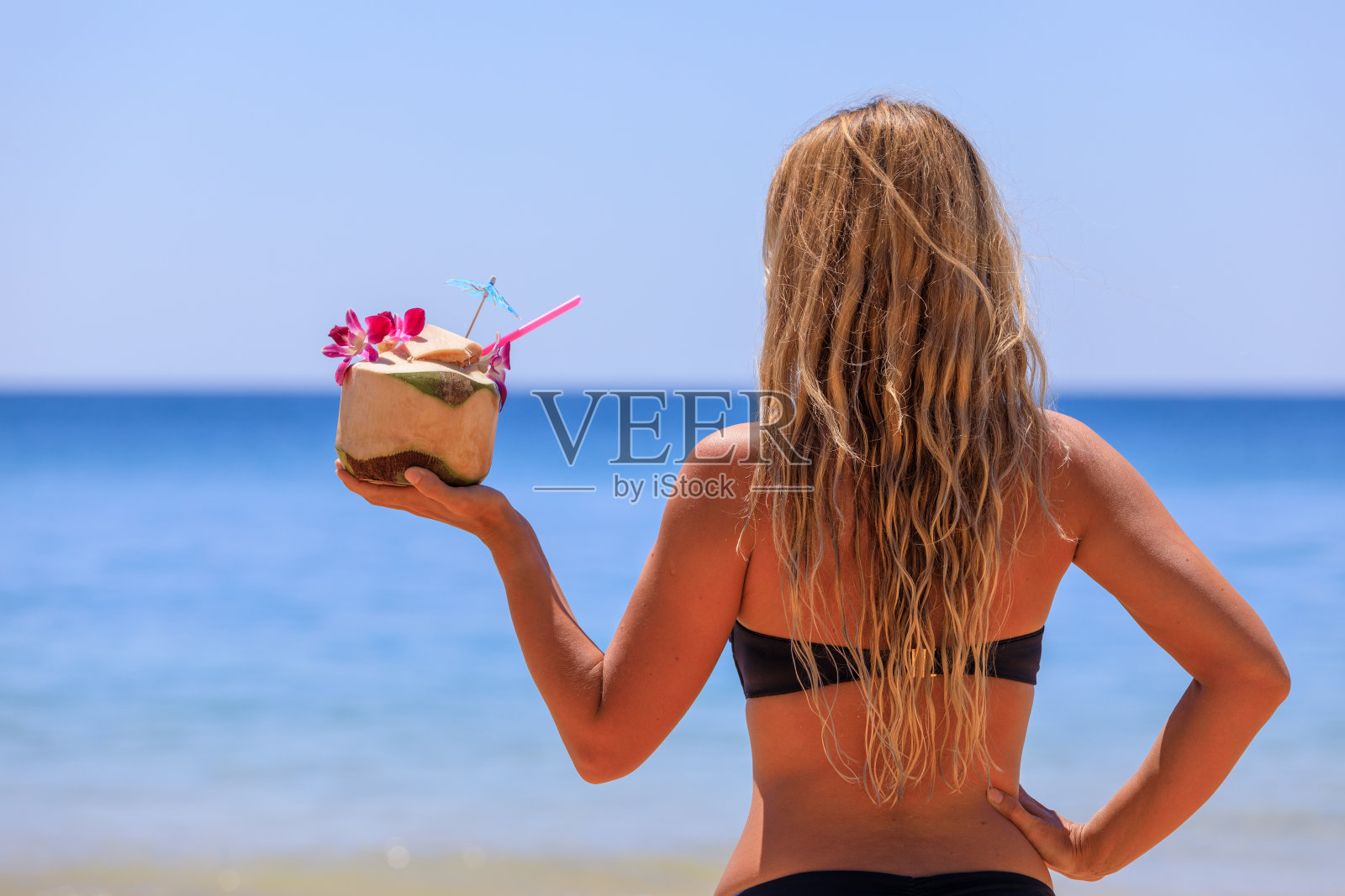 沙滩上一个穿着泳衣和椰子的漂亮女孩。照片摄影图片