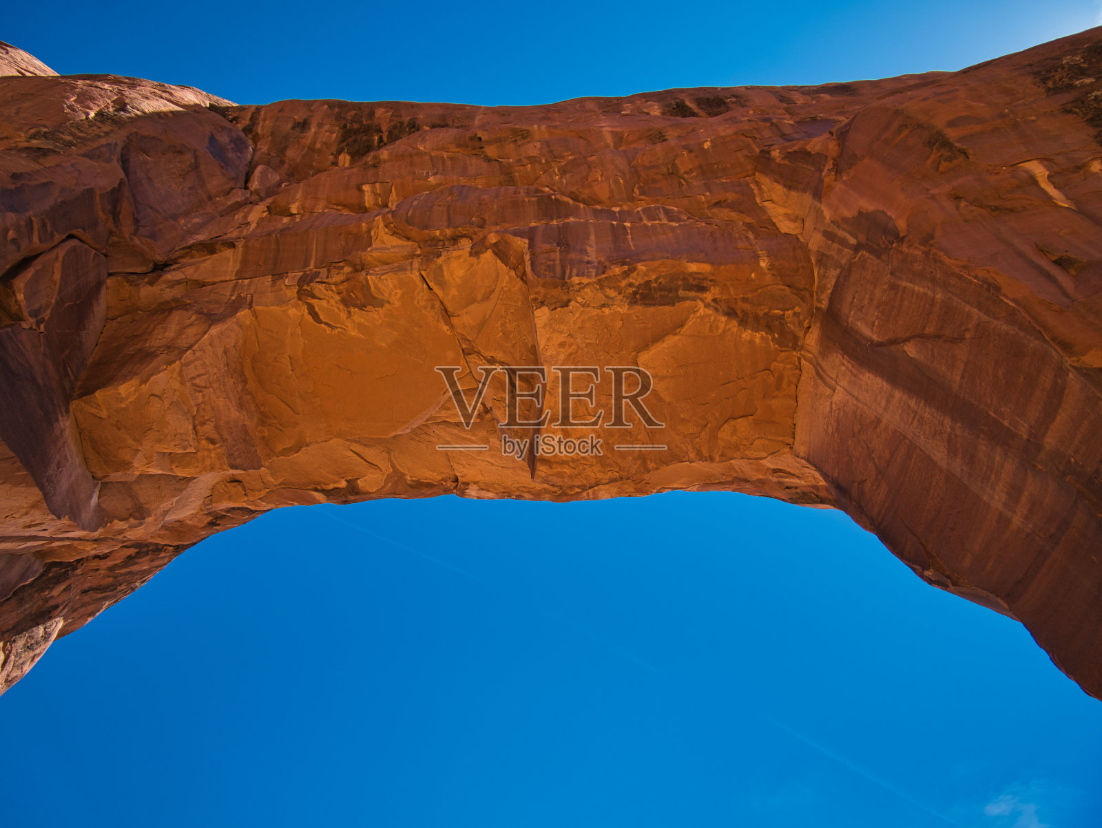 在万里无云的天空下，巨大的岩拱照片摄影图片