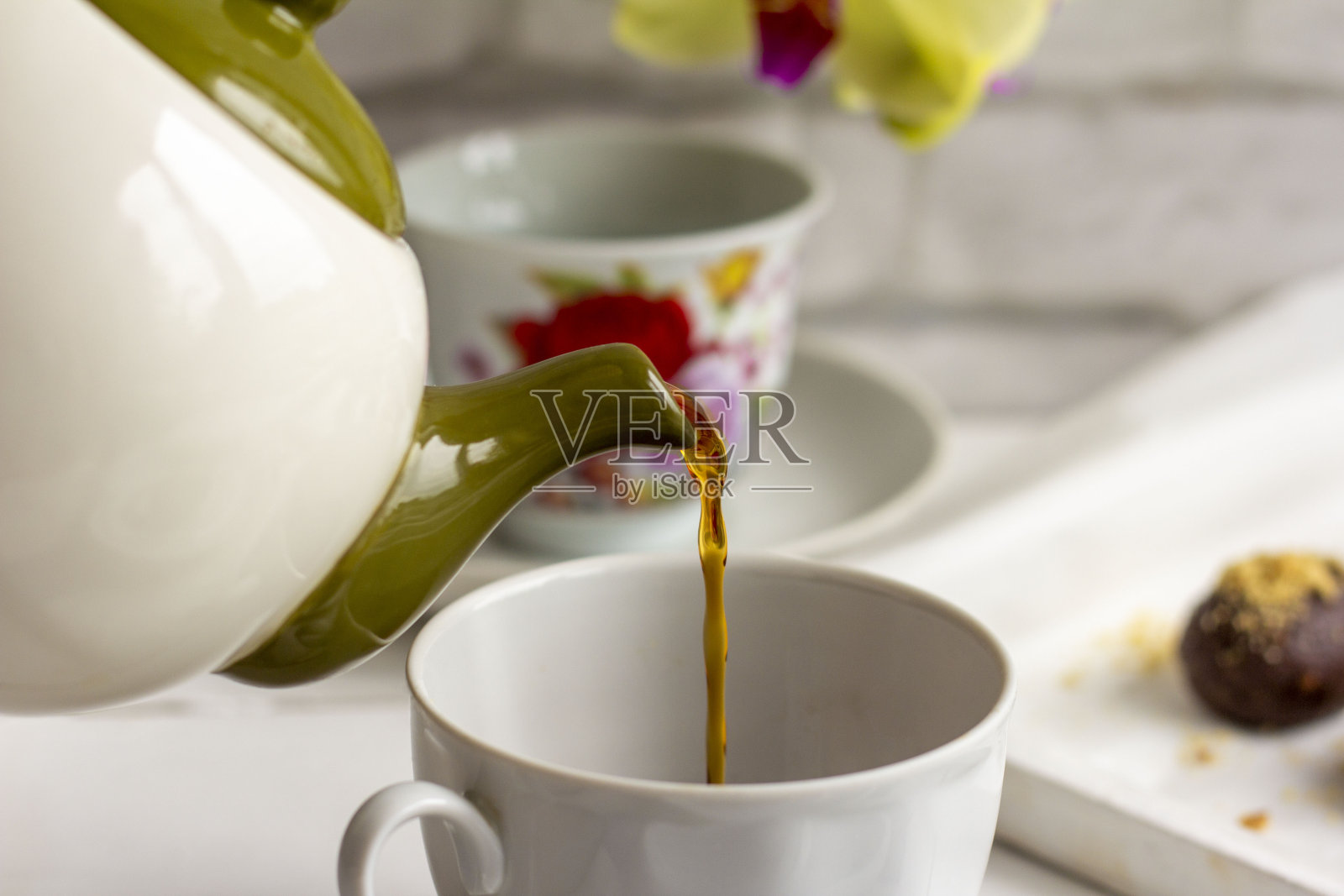 白杯里的热茶放在明亮的桌子上。端茶倒水。把茶倒进杯子里。关闭了。照片摄影图片