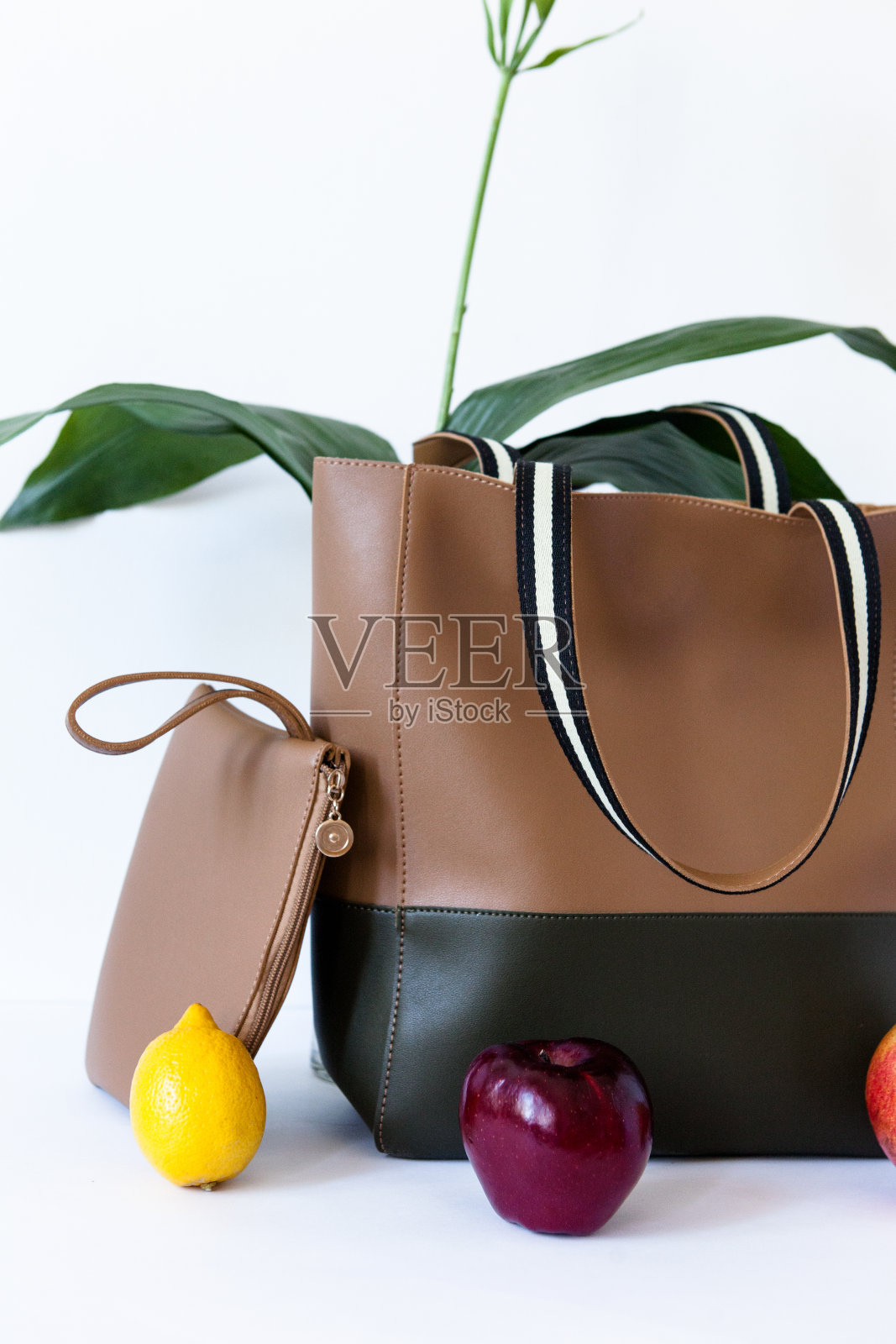 以白色为背景的时尚设计师包和钱包创意的水果和计划的静物构图广告创意照片摄影图片