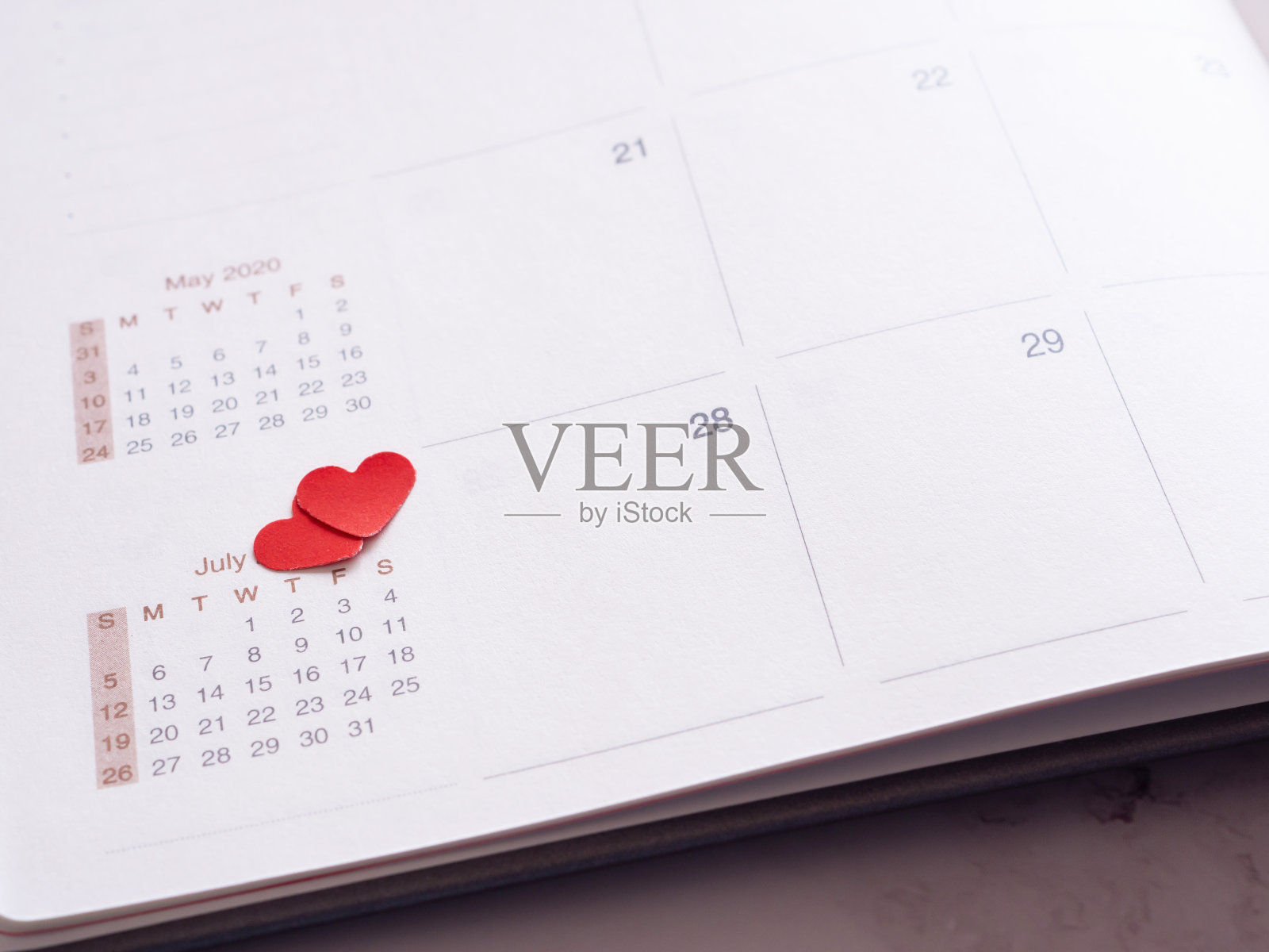 心形的红纸在七月的一个月的日记里，在灰色的背景上。照片摄影图片