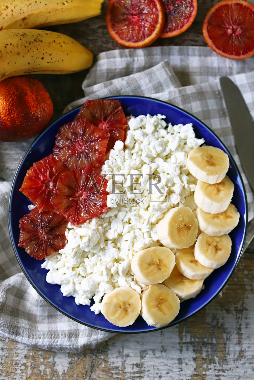 一盘白软干酪，香蕉和红橙。照片摄影图片
