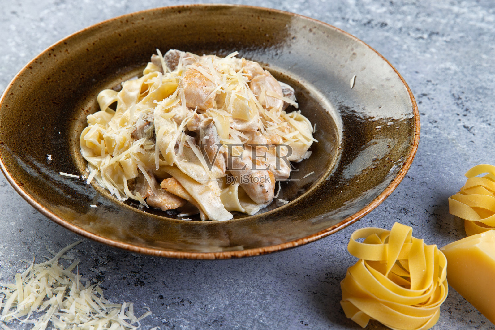 灰色背景的盘子里有鸡肉和蘑菇的意大利面照片摄影图片