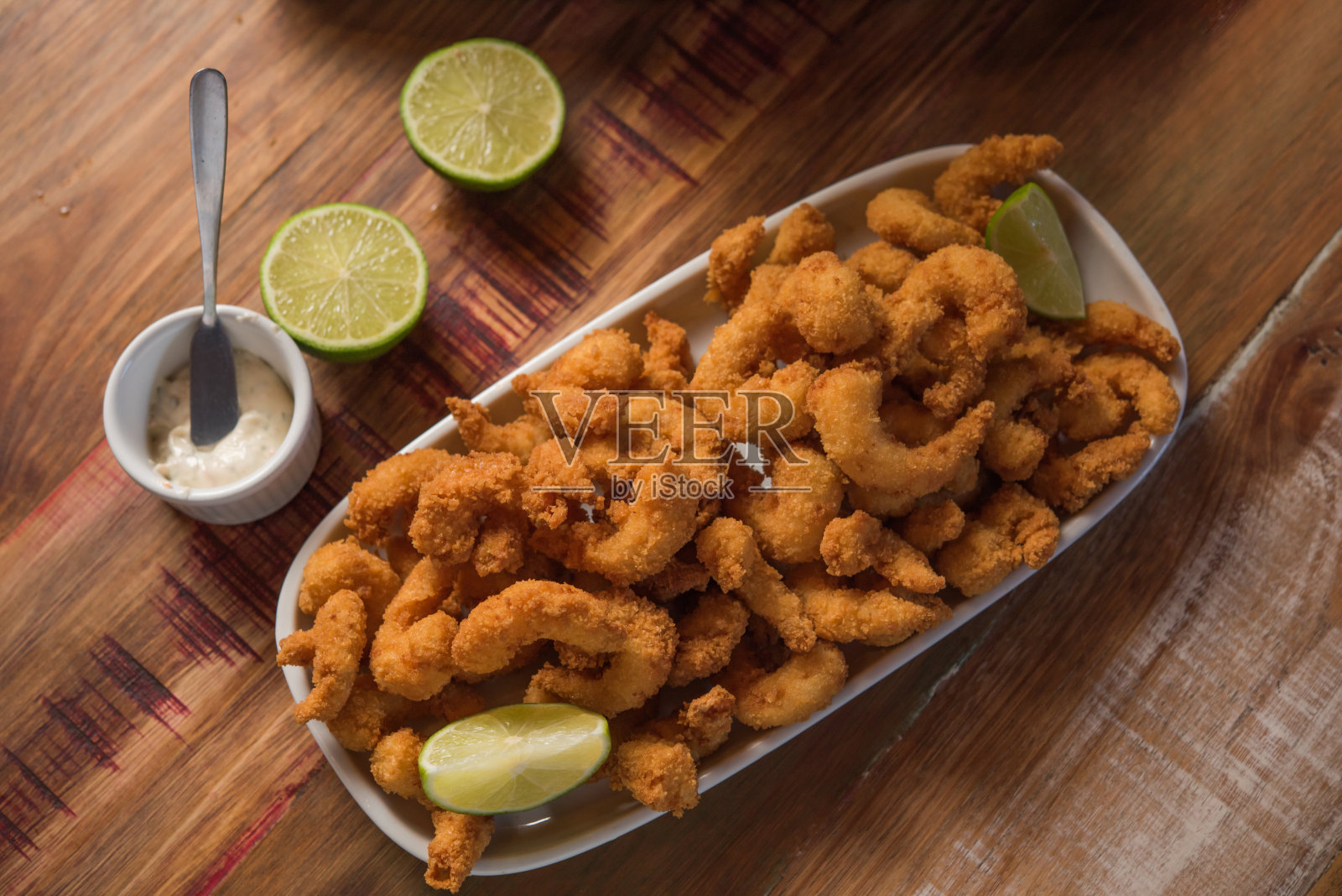 面包屑虾(Milanesa)的俯视图，盛在一张质朴的木桌上，用柠檬装饰照片摄影图片