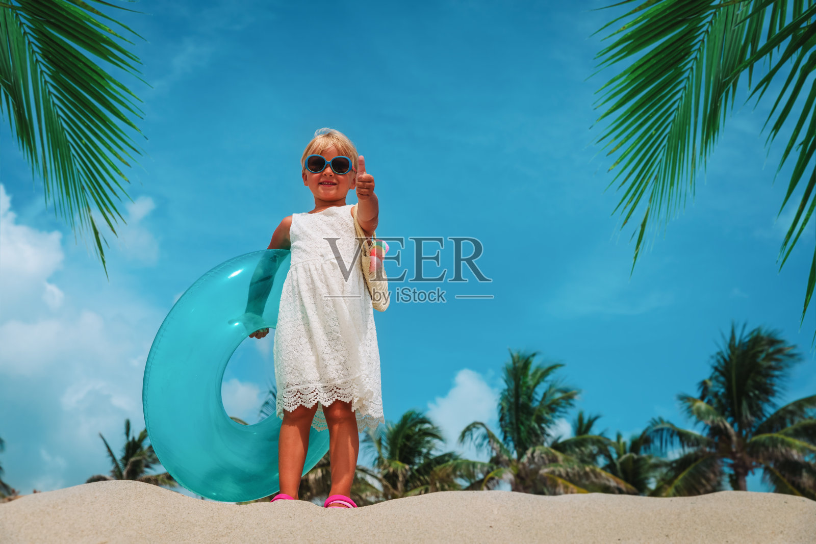 可爱的小女孩在沙滩上竖起大拇指照片摄影图片