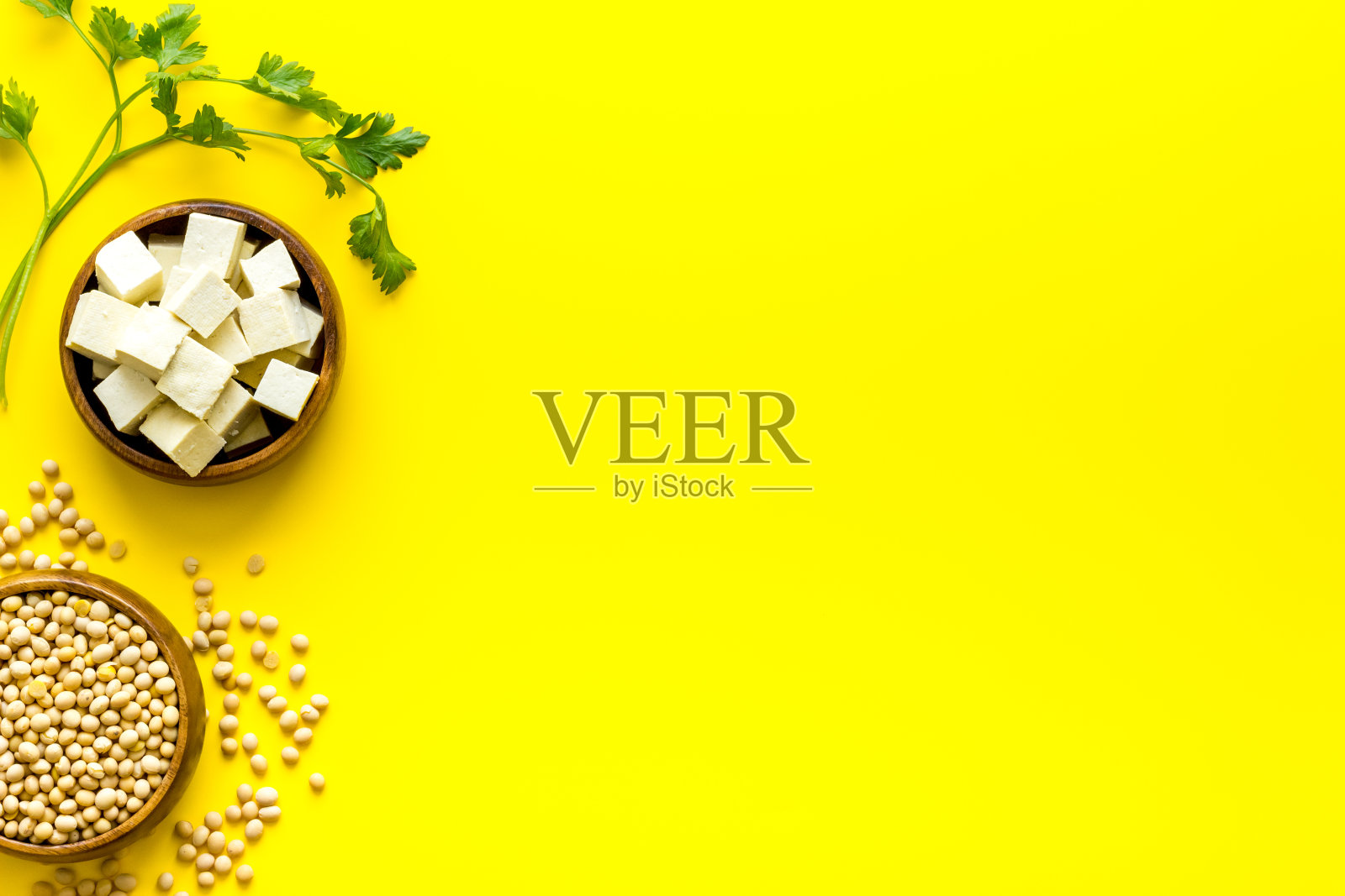 碗里的豆腐块和黄色桌子上的黄豆照片摄影图片