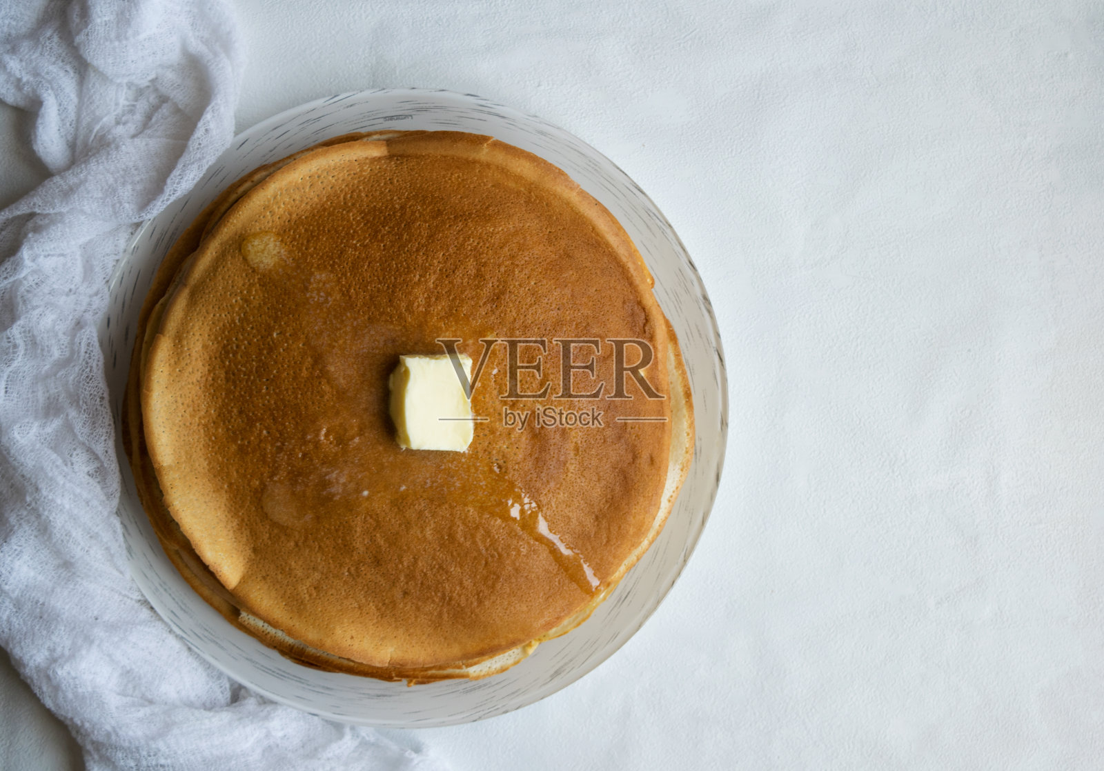 一堆薄煎饼，一片黄油在明亮的背景上。照片摄影图片