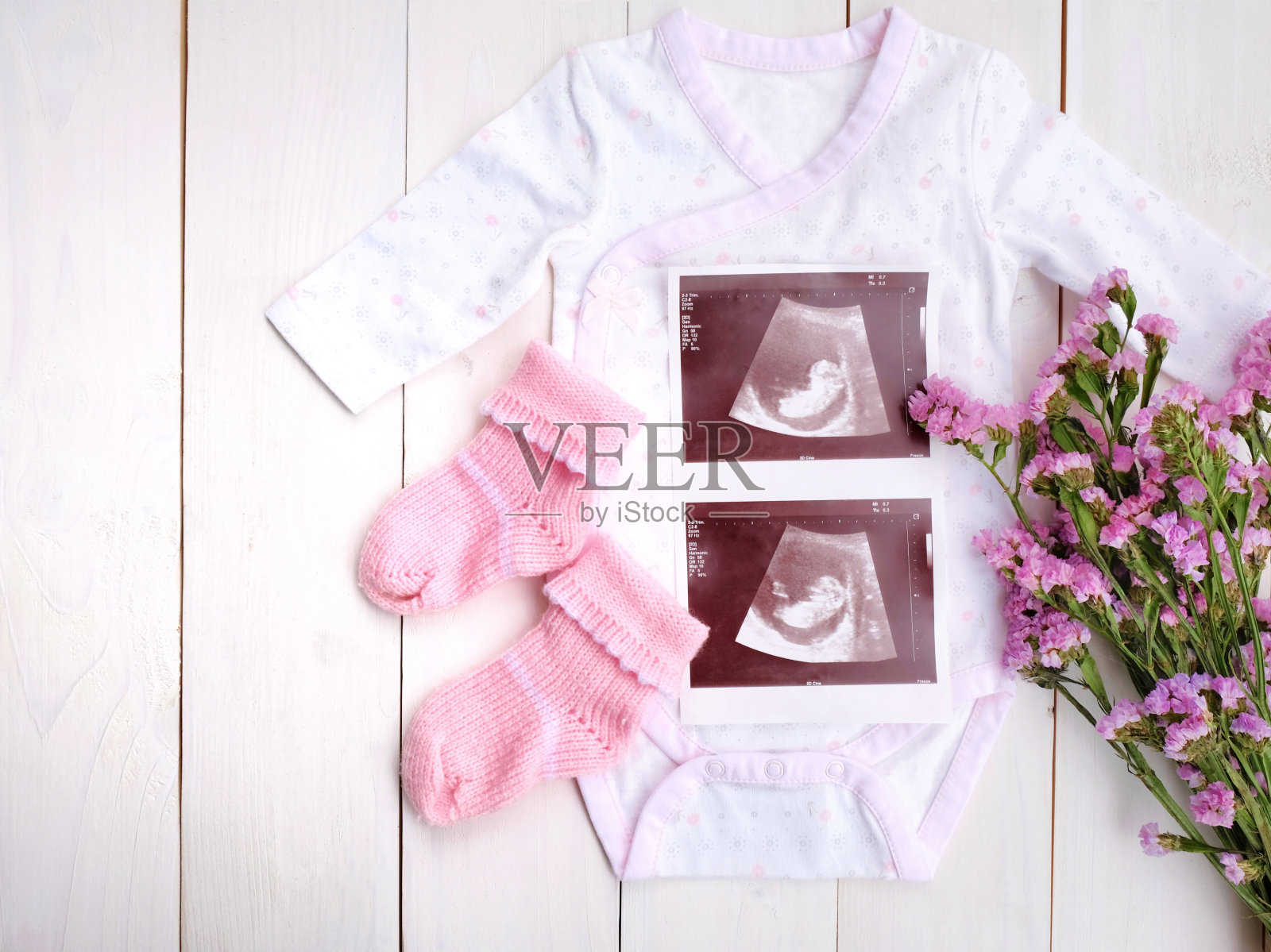 婴儿布与2d超声婴儿和紫色的花在白色木制背景。怀孕lch的概念。照片摄影图片
