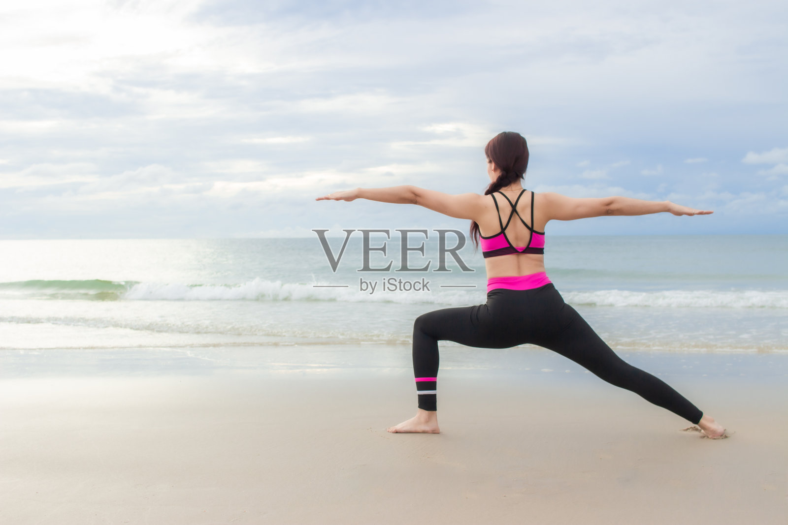 一个年轻女子早上在沙滩上练习瑜伽照片摄影图片