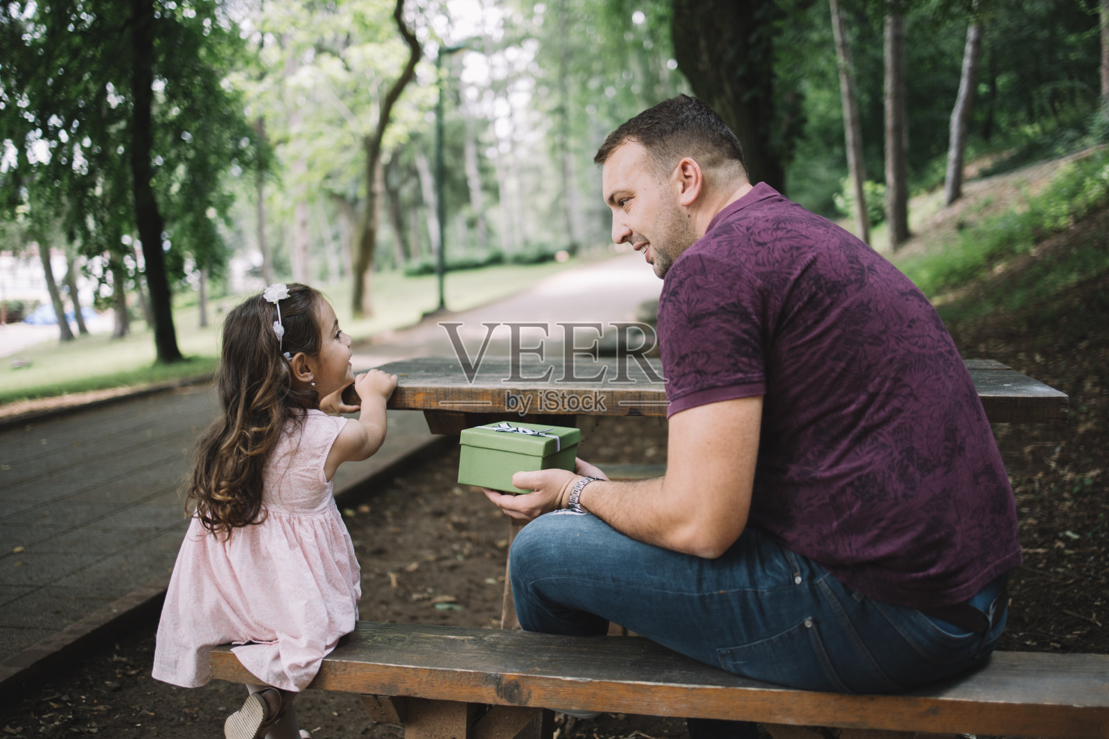 侧视图的女儿和父亲在长凳上拿着礼盒照片摄影图片