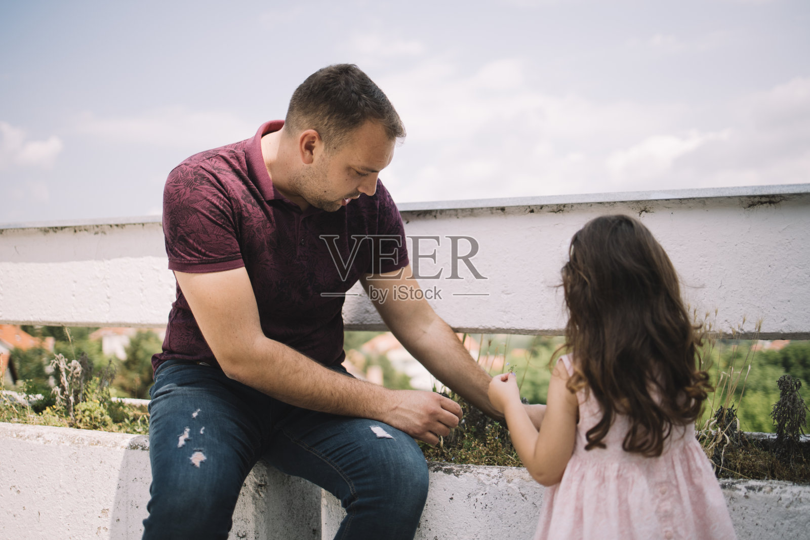 小女孩和她的父亲抚摸石制花盆里的植物照片摄影图片
