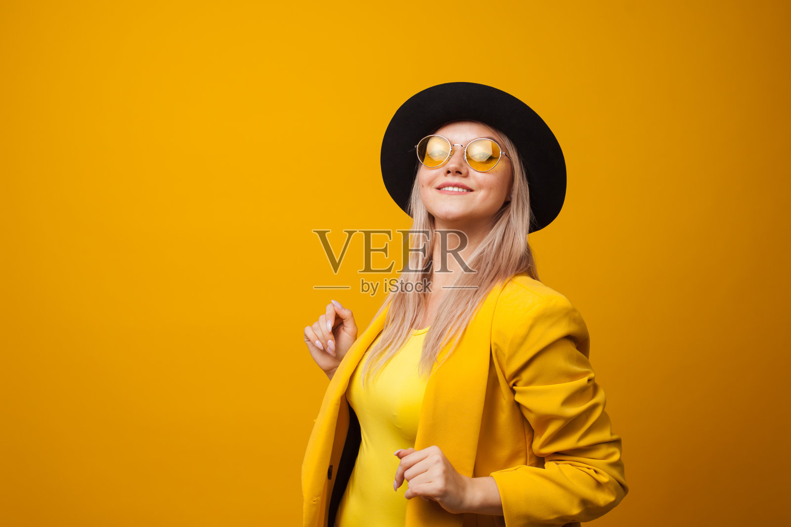 开朗潮流的年轻女子在明亮的黄色背景上，复制空间。酷的金发女郎照片摄影图片