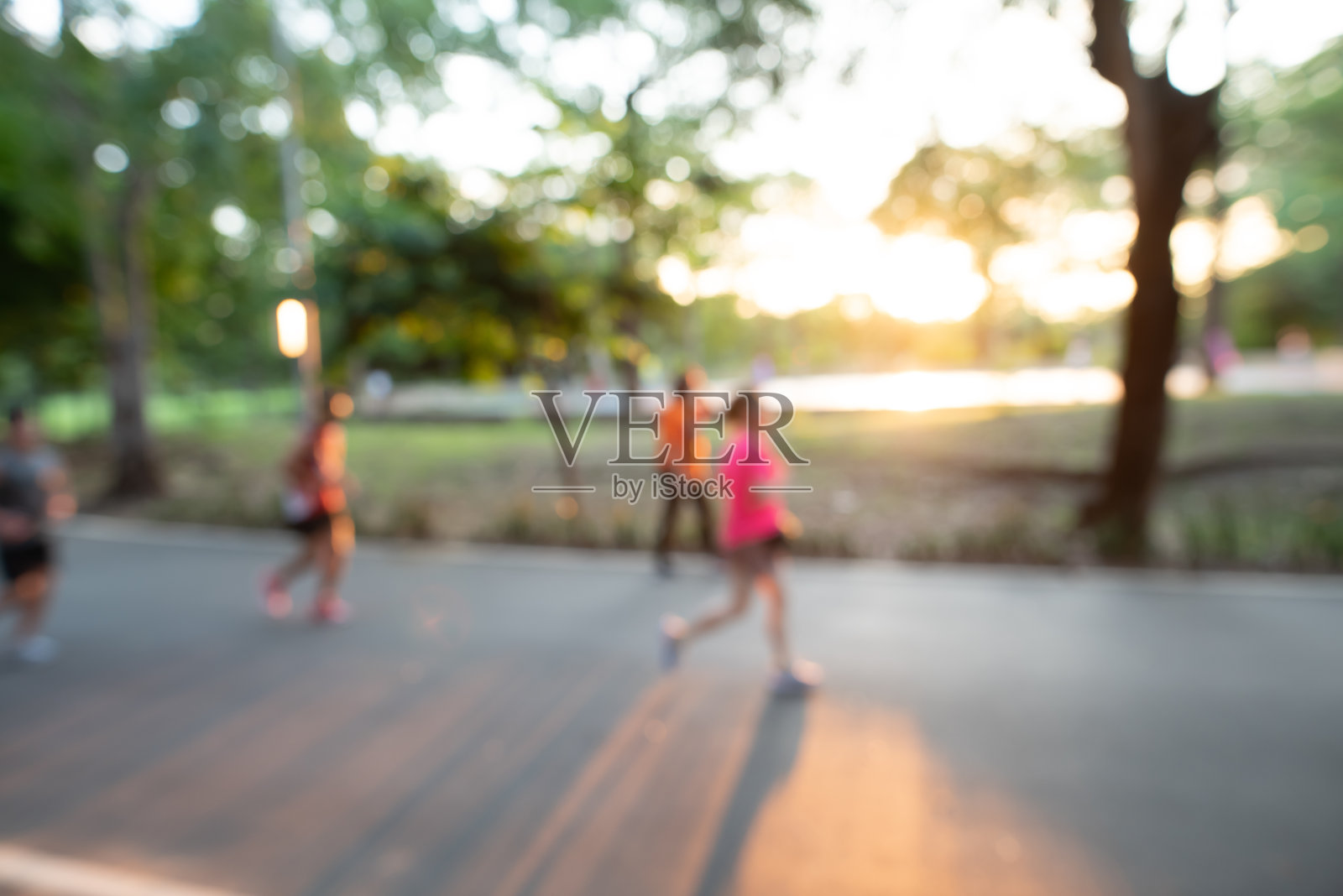 模糊背景下的人们在公园里跑步和活动，健康的生活方式理念。照片摄影图片