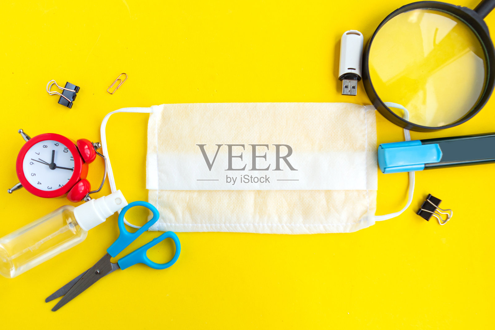 亮黄色背景上是学校用品和医用口罩，俯视图。回到学校观念，隔离学校观念照片摄影图片