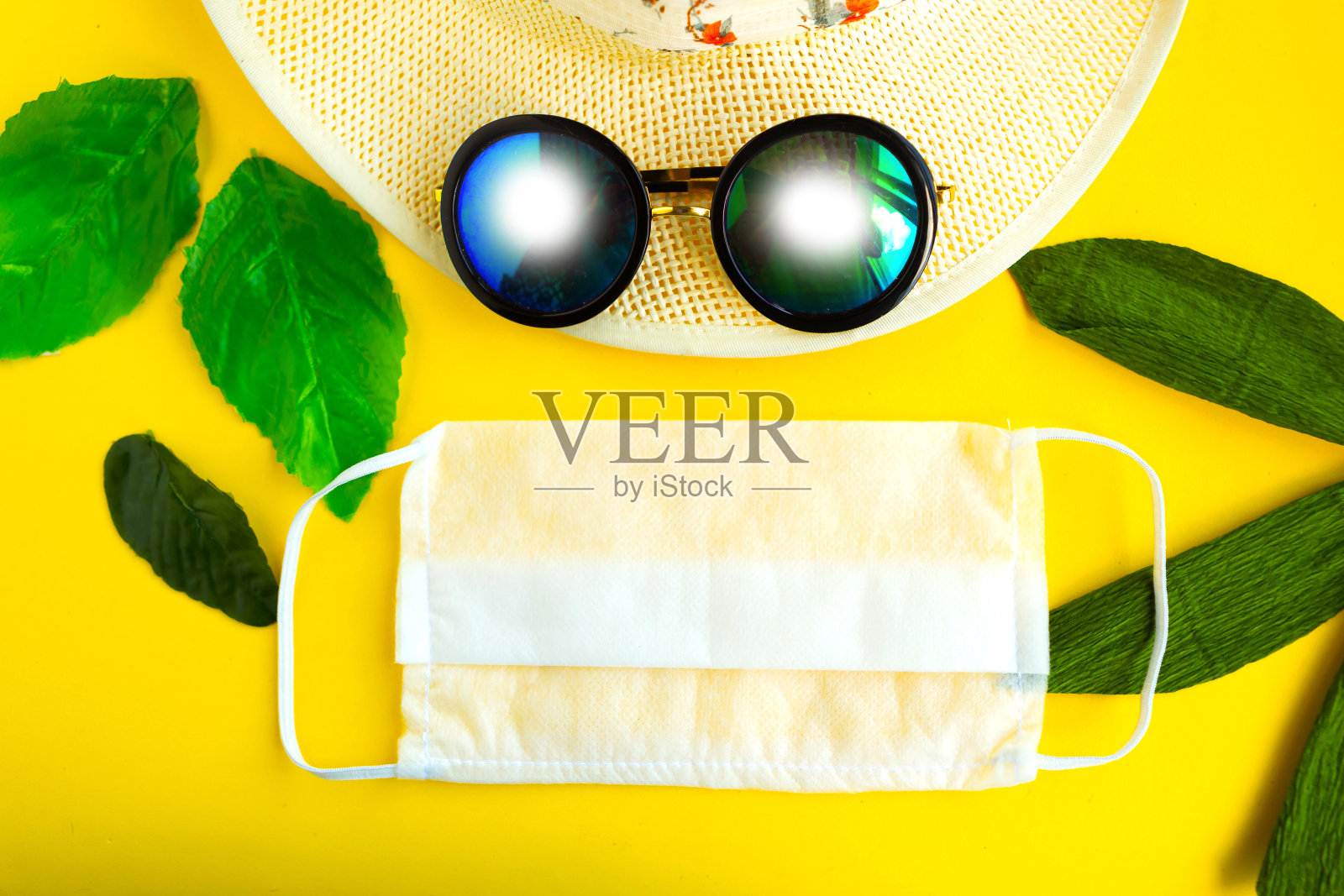 草帽、太阳镜和医用口罩，背景为亮黄色。冠状病毒旅游概念照片摄影图片