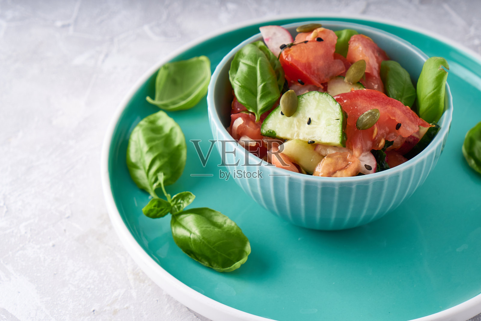 健康食品。将新鲜的夏季蔬菜，新鲜的罗勒，番茄，洋葱，黄瓜，芝麻混合成一碗沙拉照片摄影图片