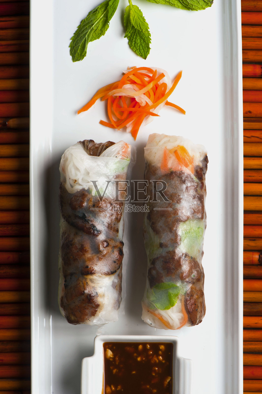 春卷，经典的越南，泰国，中国或韩国开胃菜。米纸里塞满粉丝面，虾，胡萝卜和虾。配花生和酸甜辣酱。照片摄影图片