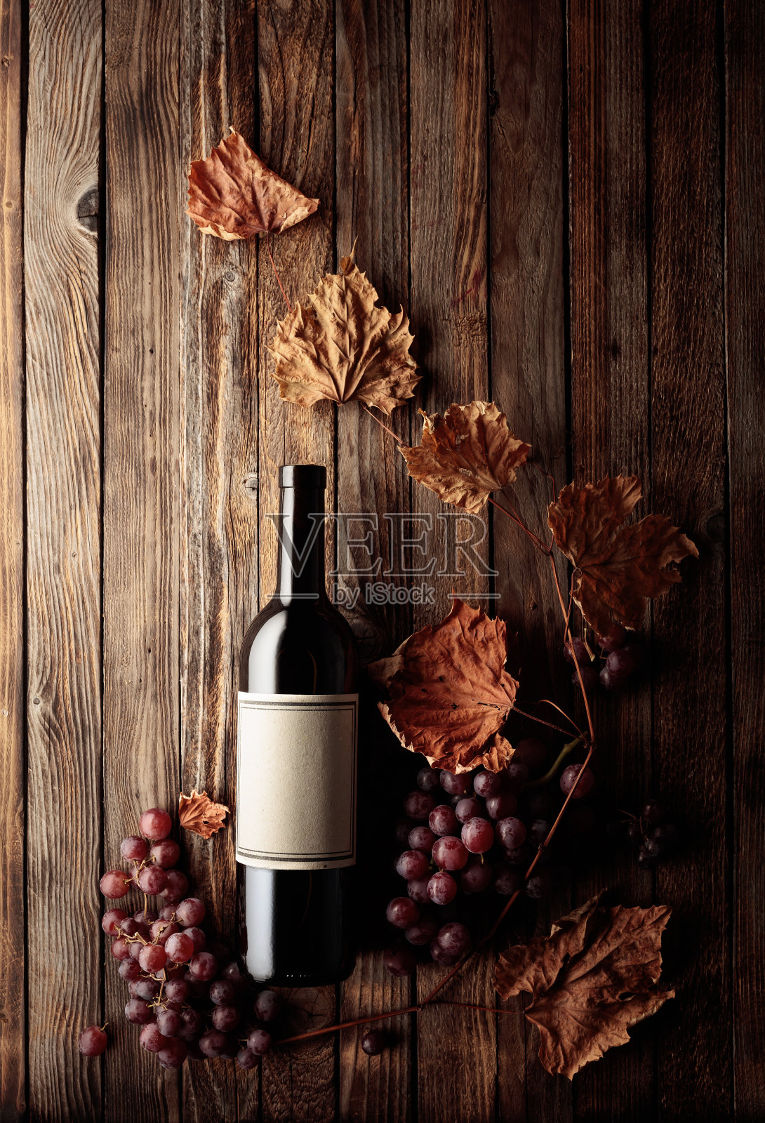 一瓶红酒，里面有成熟的葡萄和干枯的藤叶。照片摄影图片