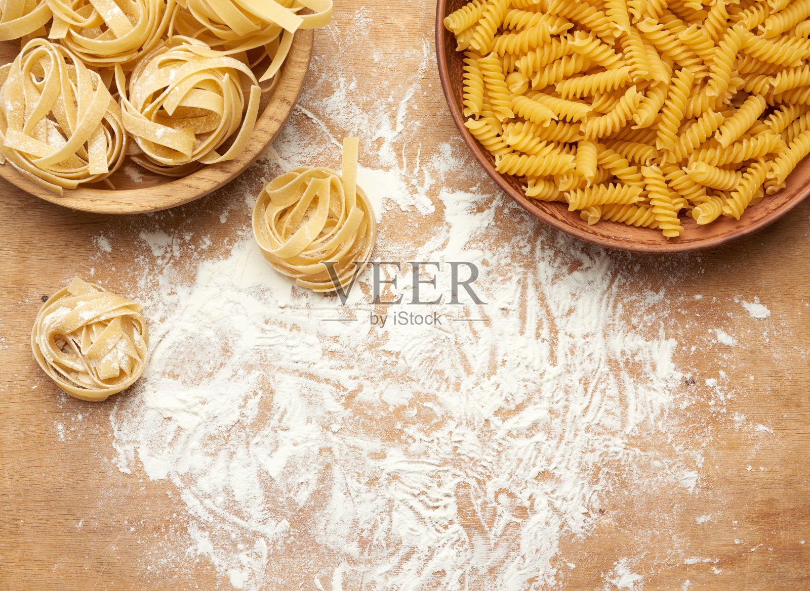 在棕色的木桌上，木盘里装着生意大利面和宽面条照片摄影图片