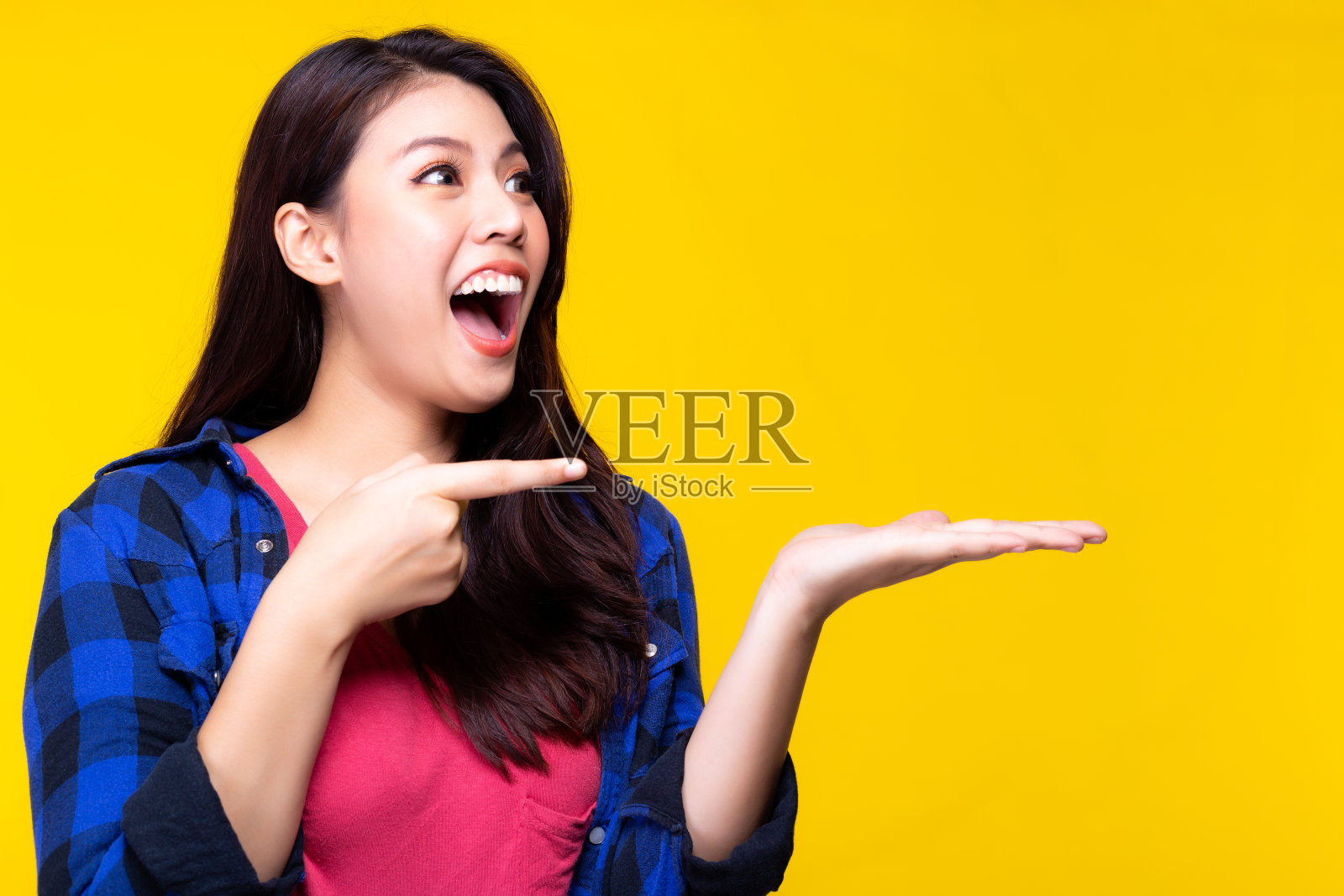 迷人美丽的年轻女子指指点点，看着美丽的产品。美夫人看到品在手心里大吃一惊，震惊不已。漂亮女孩感到快乐。广告,商业。本空间照片摄影图片