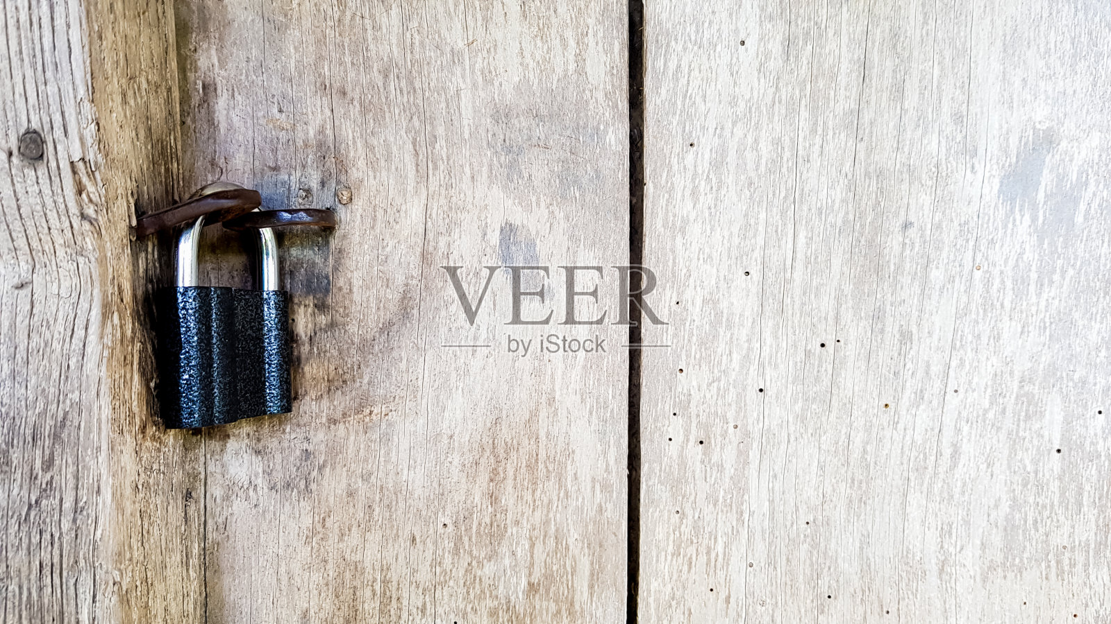古老的金属挂锁在一个古老的农舍的紧闭的木门上。真正的乡村风格。特写镜头。木制背景纹理。本空间照片摄影图片
