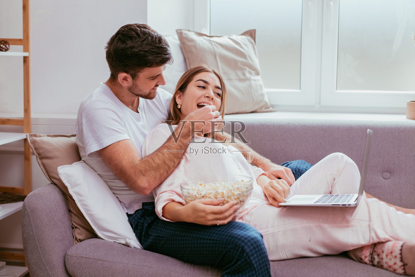 幸福情侣在舒适的客厅沙发上拥抱、玩耍，一起看笔记本电脑照片摄影图片