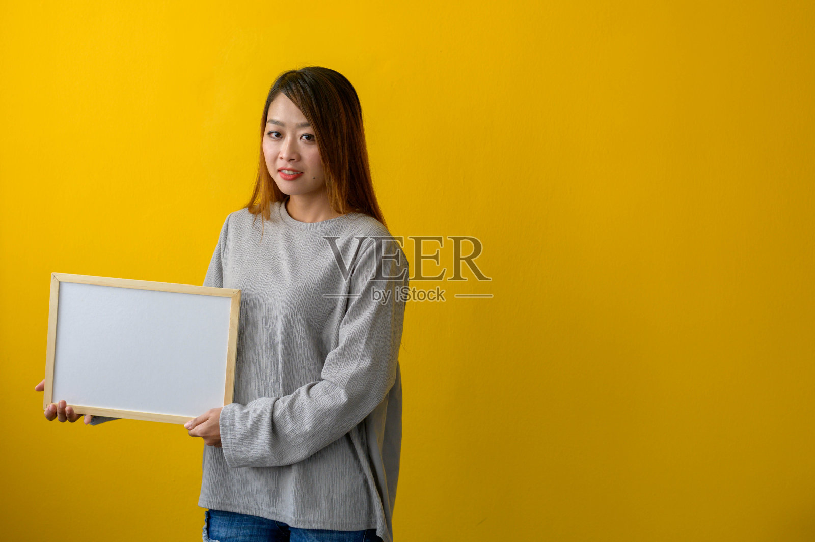 女人拿着黄色背景的白板照片摄影图片