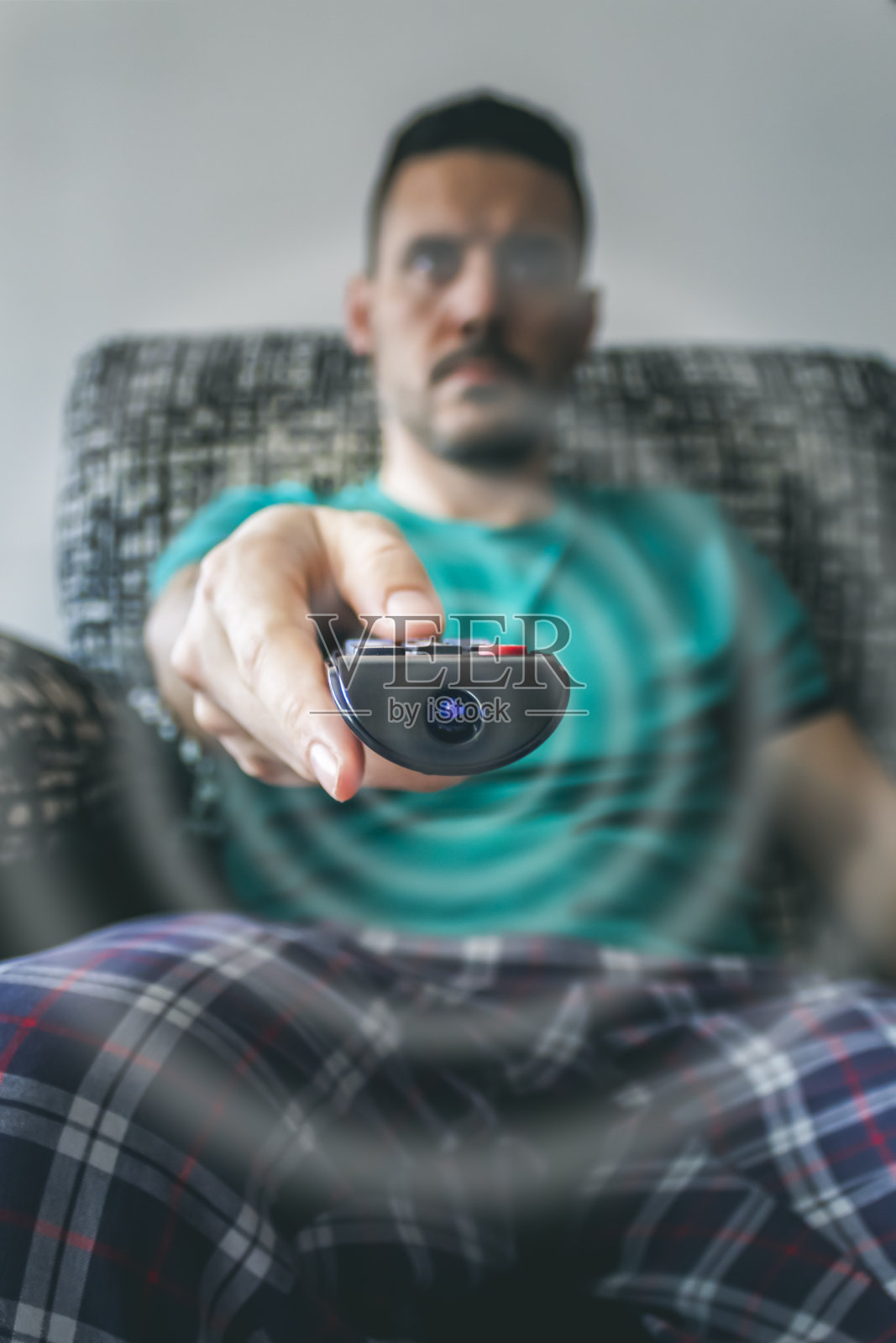 穿睡衣的男人在电视上换台。遥控器的选择方式照片摄影图片