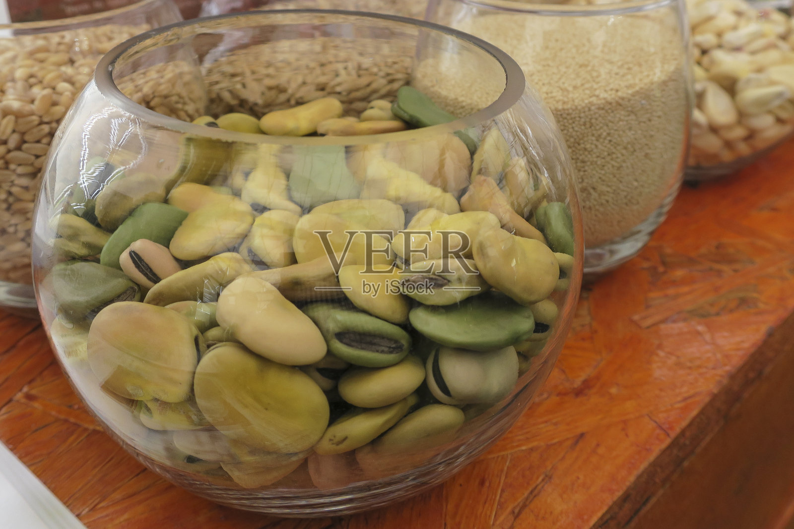 装有干蚕豆的圆形水晶碗。(蚕豆根尖)照片摄影图片