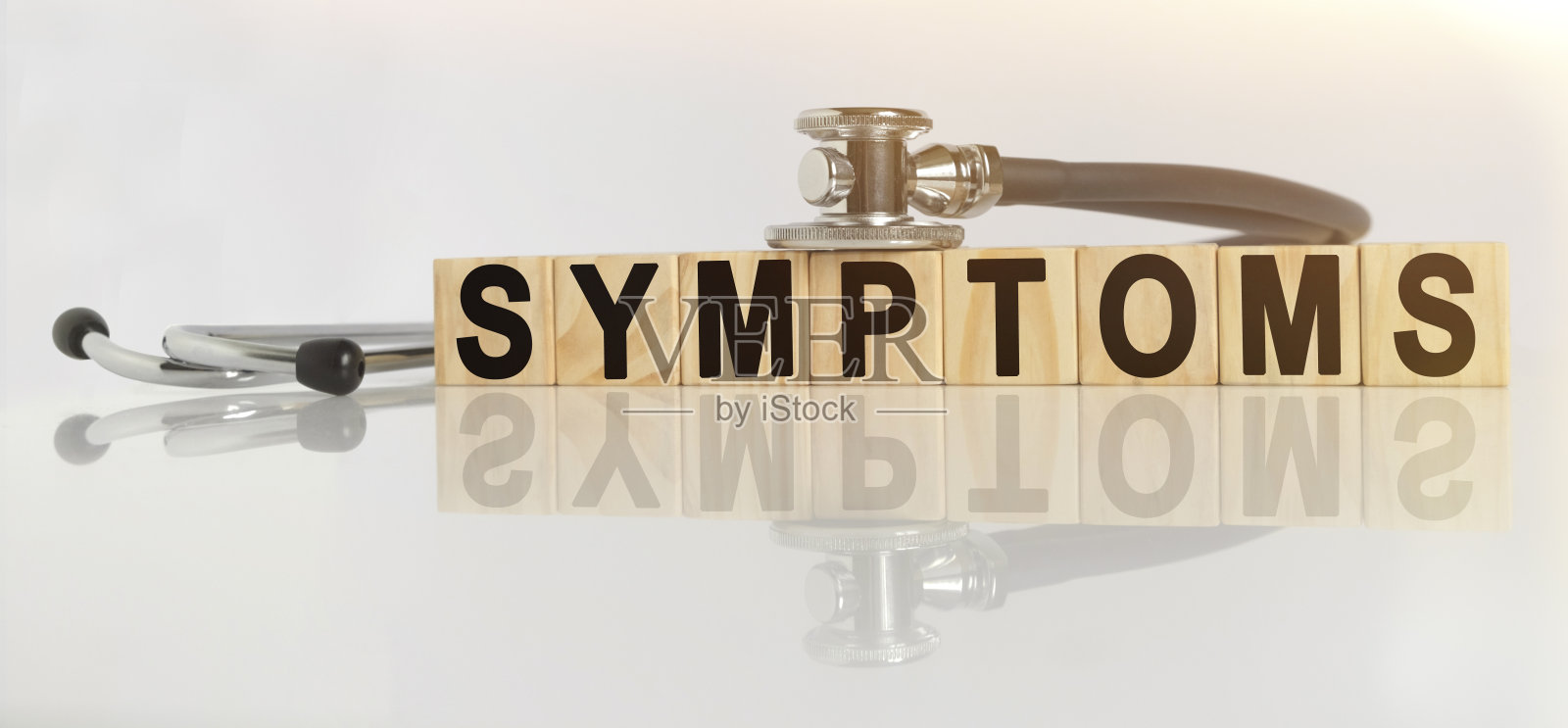 症状一词就在木质立方体上，立方体站在反射的白色表面上，立方体上——听诊器。照片摄影图片