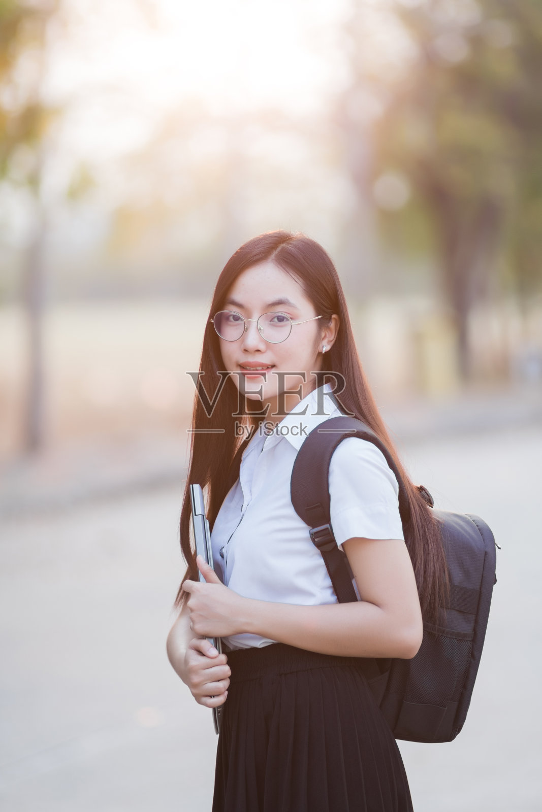 年轻的亚洲女大学生背包拿着笔记本电脑在大学校园。女大学生上大学。回到学校的概念。照片摄影图片