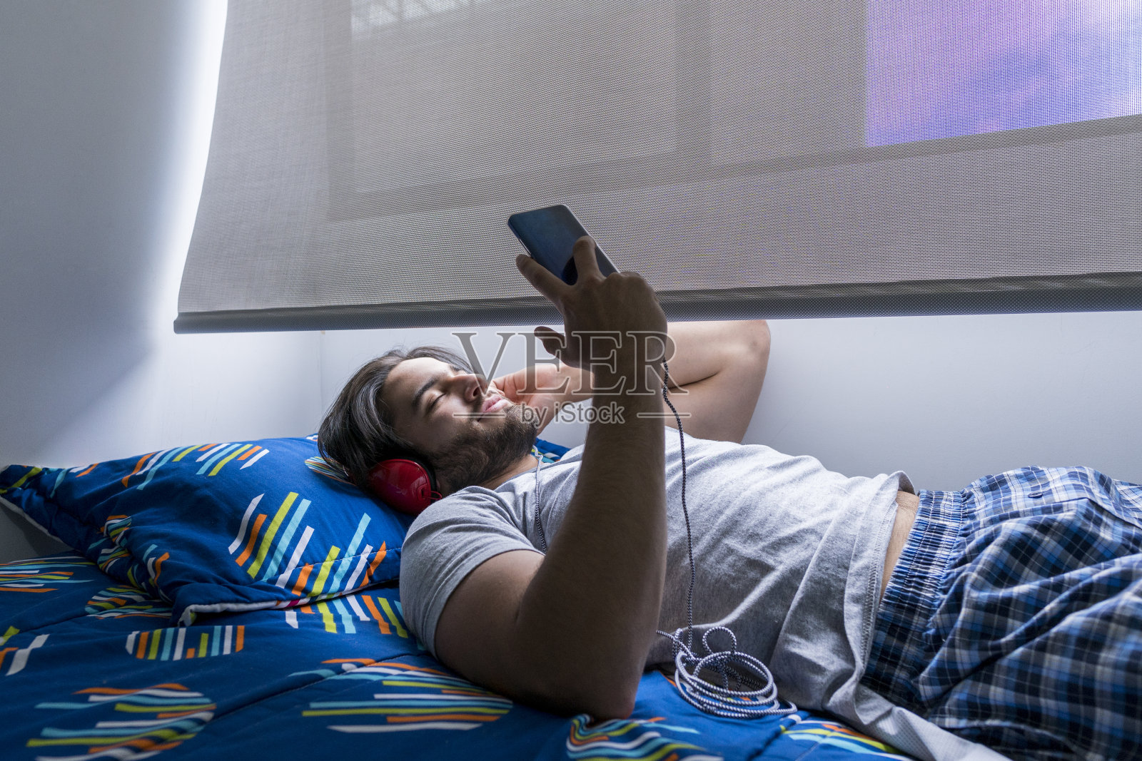 男人喜欢边听音乐边在窗边晒日光浴照片摄影图片