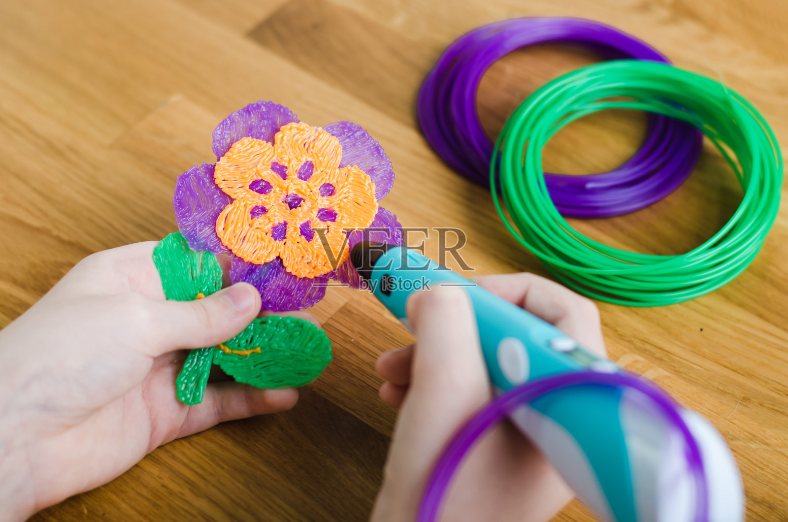 孩子使用3D笔。孩子们用彩色ABS塑料制作花朵。照片摄影图片