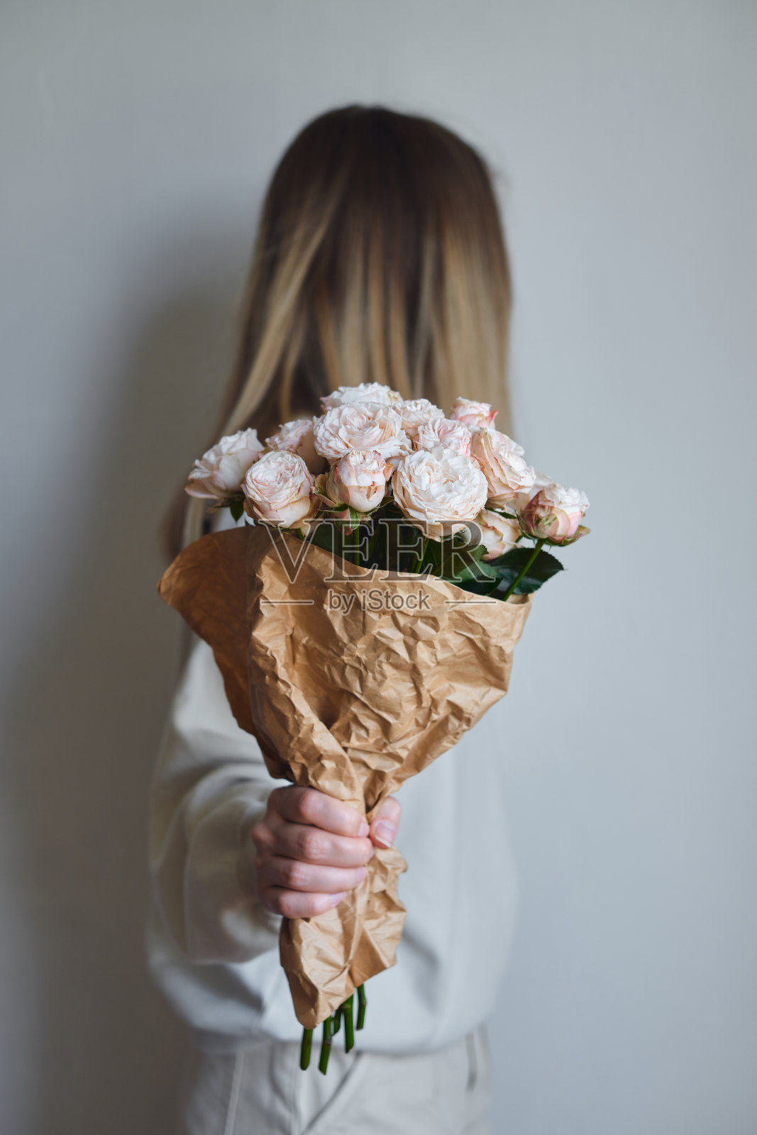 一个幸福女人手里捧着白玫瑰。玫瑰花瓣特写。美丽的节日春天花束。卖花女孩拿着盛开的花朵。新鲜的植物群。来自爱人的浪漫惊喜照片摄影图片