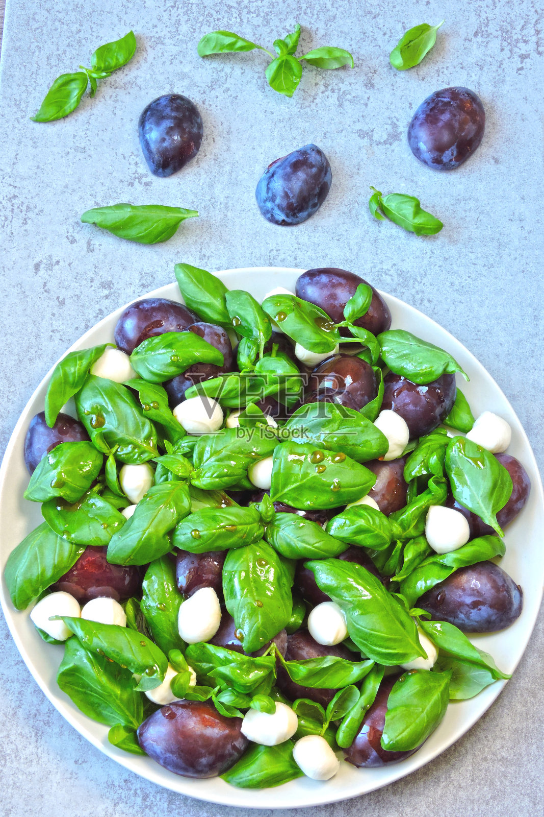 梅子，新鲜罗勒和马苏里拉奶酪球沙拉。照片摄影图片