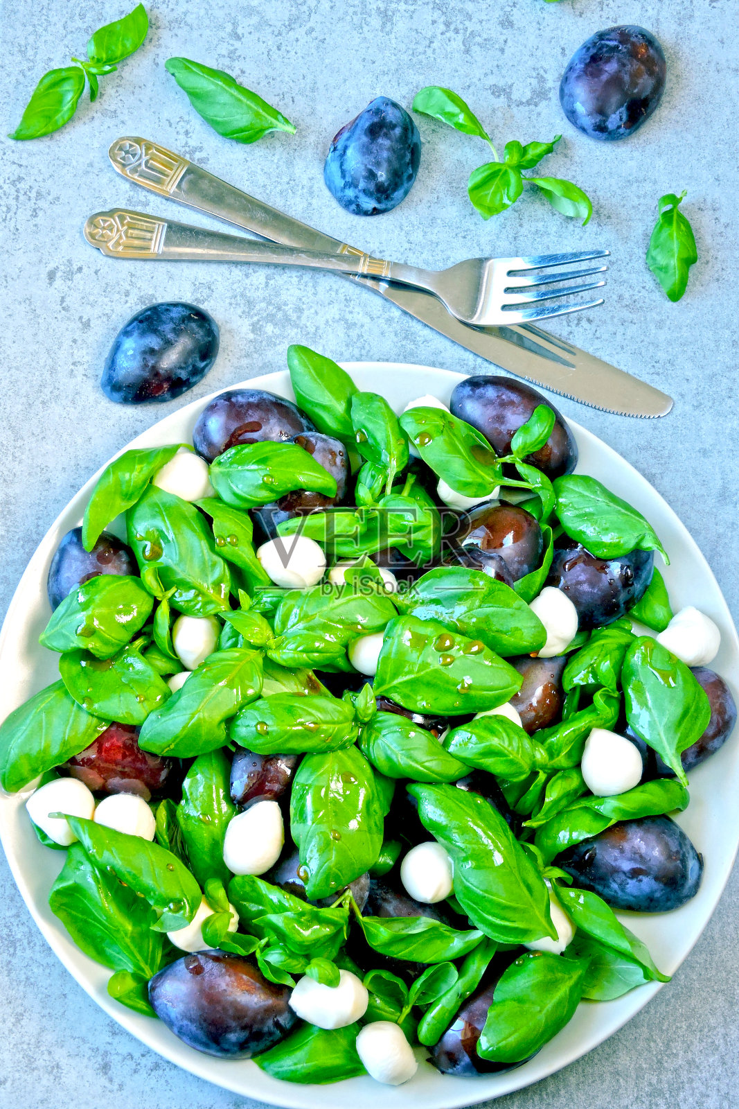 梅子，新鲜罗勒和马苏里拉奶酪球沙拉。照片摄影图片