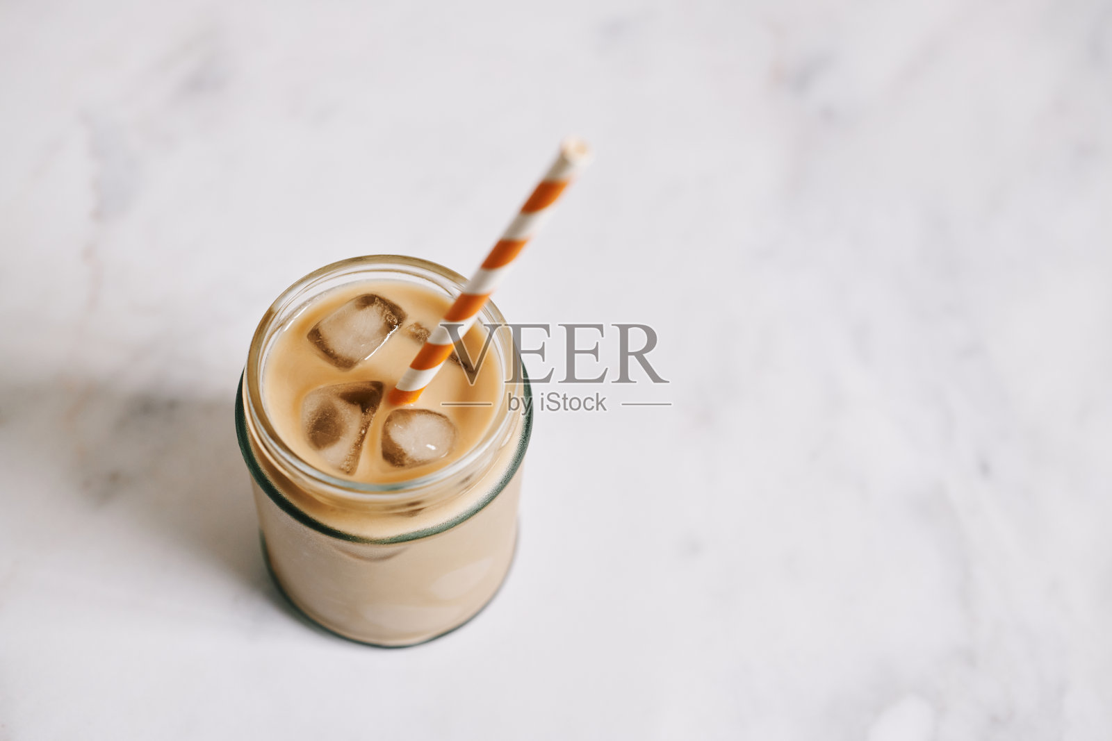 冰拿铁咖啡装在玻璃瓶里，靠在大理石桌面上。照片摄影图片