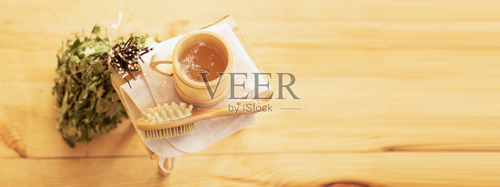 沐浴在桑拿中放松身心。蒸汽房的配件，木制家具，浴室扫把和水在杯子里。照片摄影图片