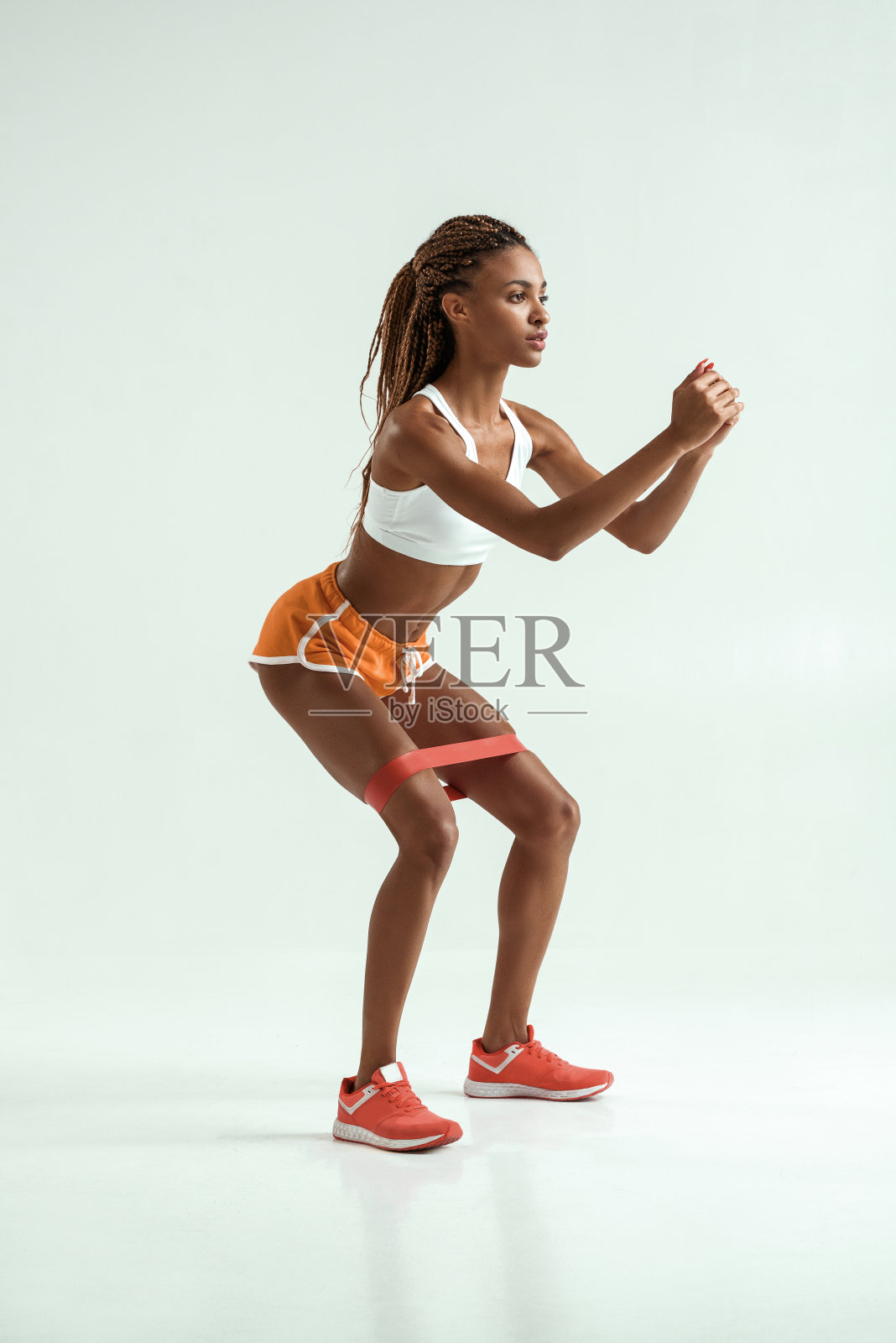 全身的年轻非洲妇女与美丽的身体做运动与阻力乐队在工作室在灰色的背景照片摄影图片