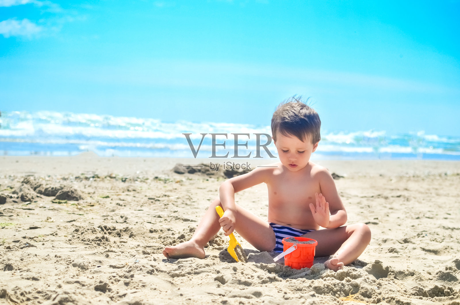 一个男孩在海边玩沙子，用沙子建城堡。夏天的心情照片摄影图片