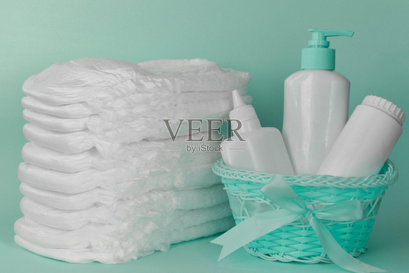 一堆干净的，现代的干燥亚麻布或尿布，绿松石背景下的卫生篮。照片摄影图片