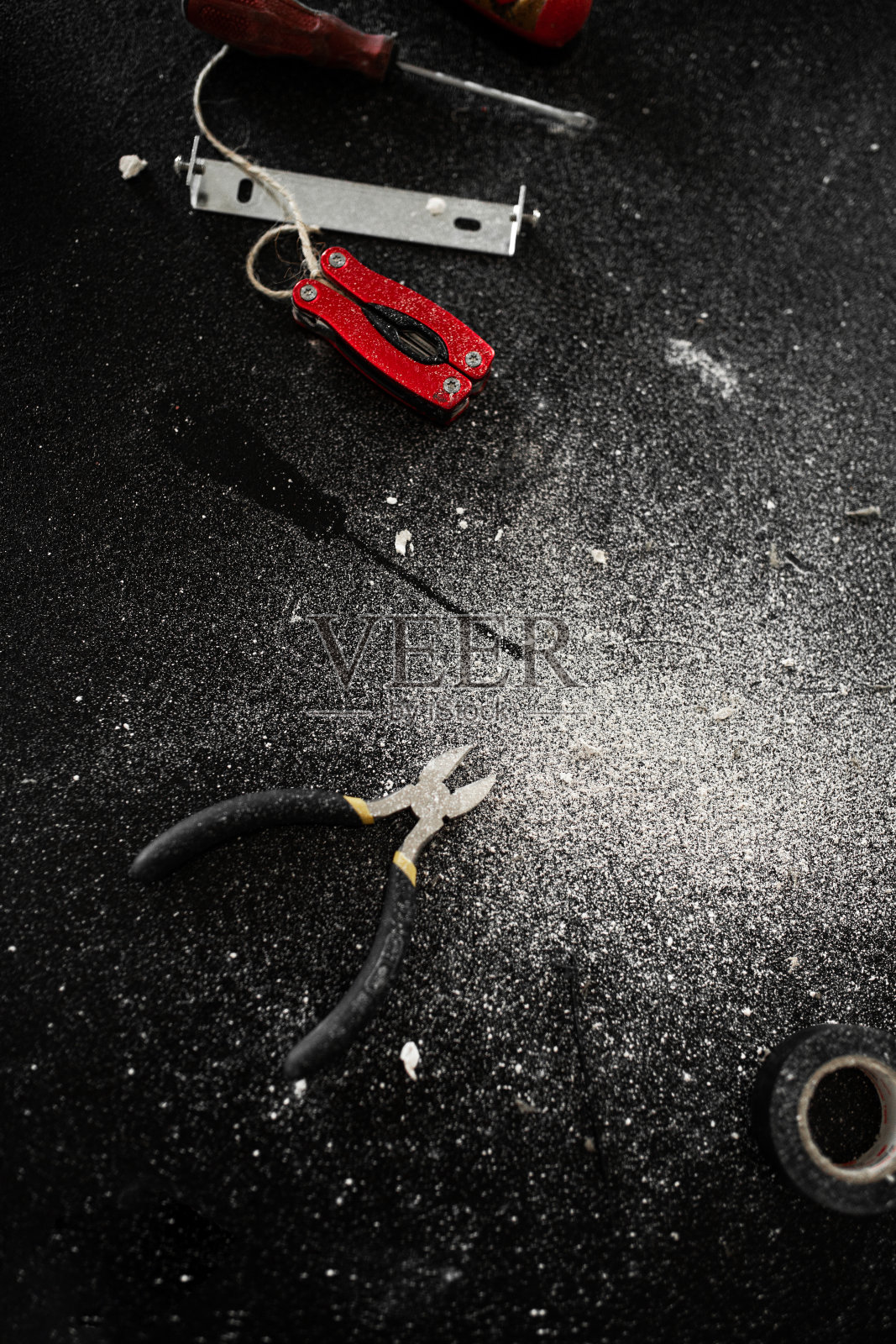 黑色的桌子上撒着白色的灰尘，上面放着一套自装灯的工具。一个小时的丈夫。家务活。照片摄影图片