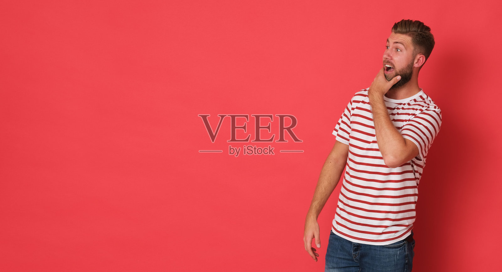 快乐的年轻人穿着白衬衫和红色条纹看起来兴奋。照片摄影图片